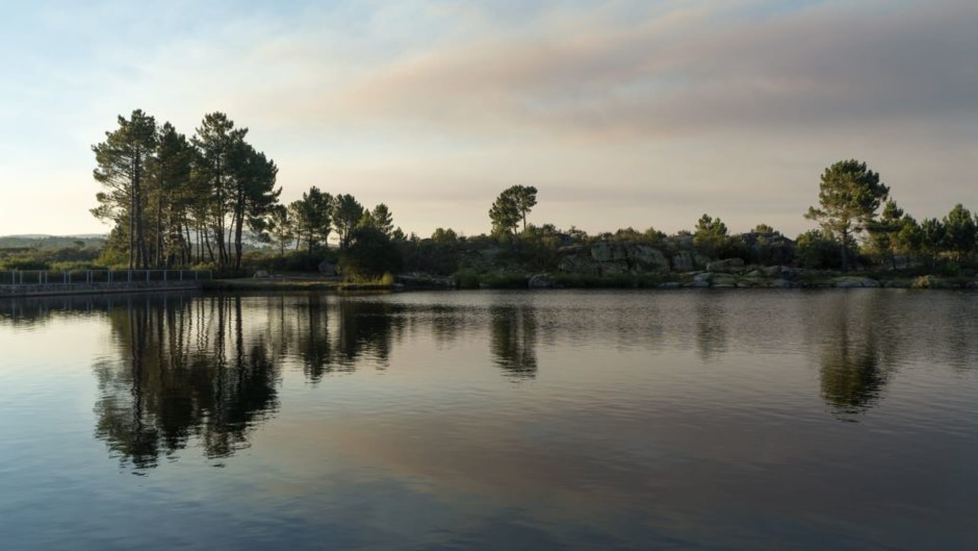 The Presa Villa Victoria reservoir in the cold Mazahua highlands west of Toluca, still water ringed by pine forest and farmland under a misty morning sky