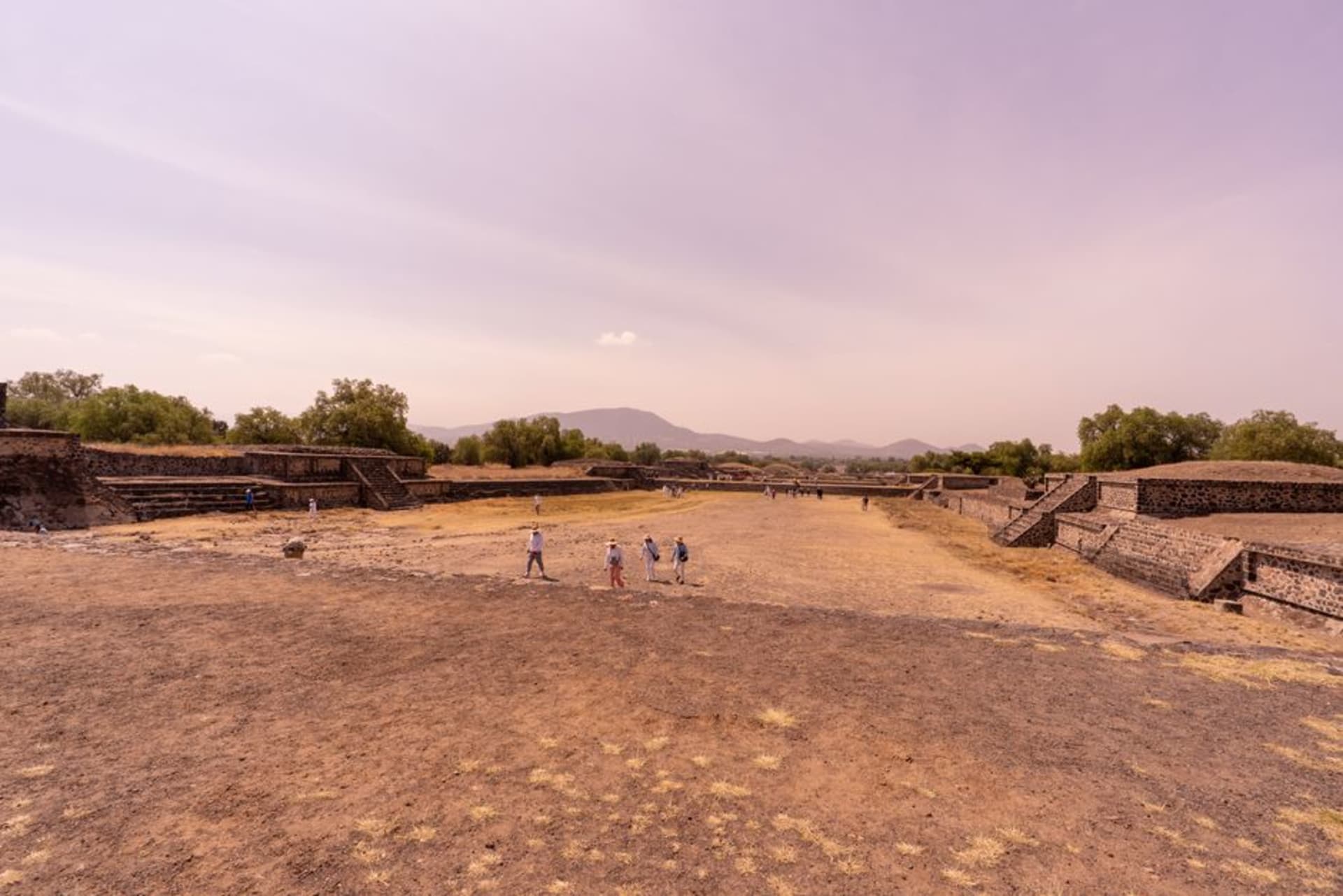 The broad stone terraces of Xochitécatl rising in morning light against a wide Tlaxcala sky, with the snow-capped cone of La Malinche filling the horizon behind