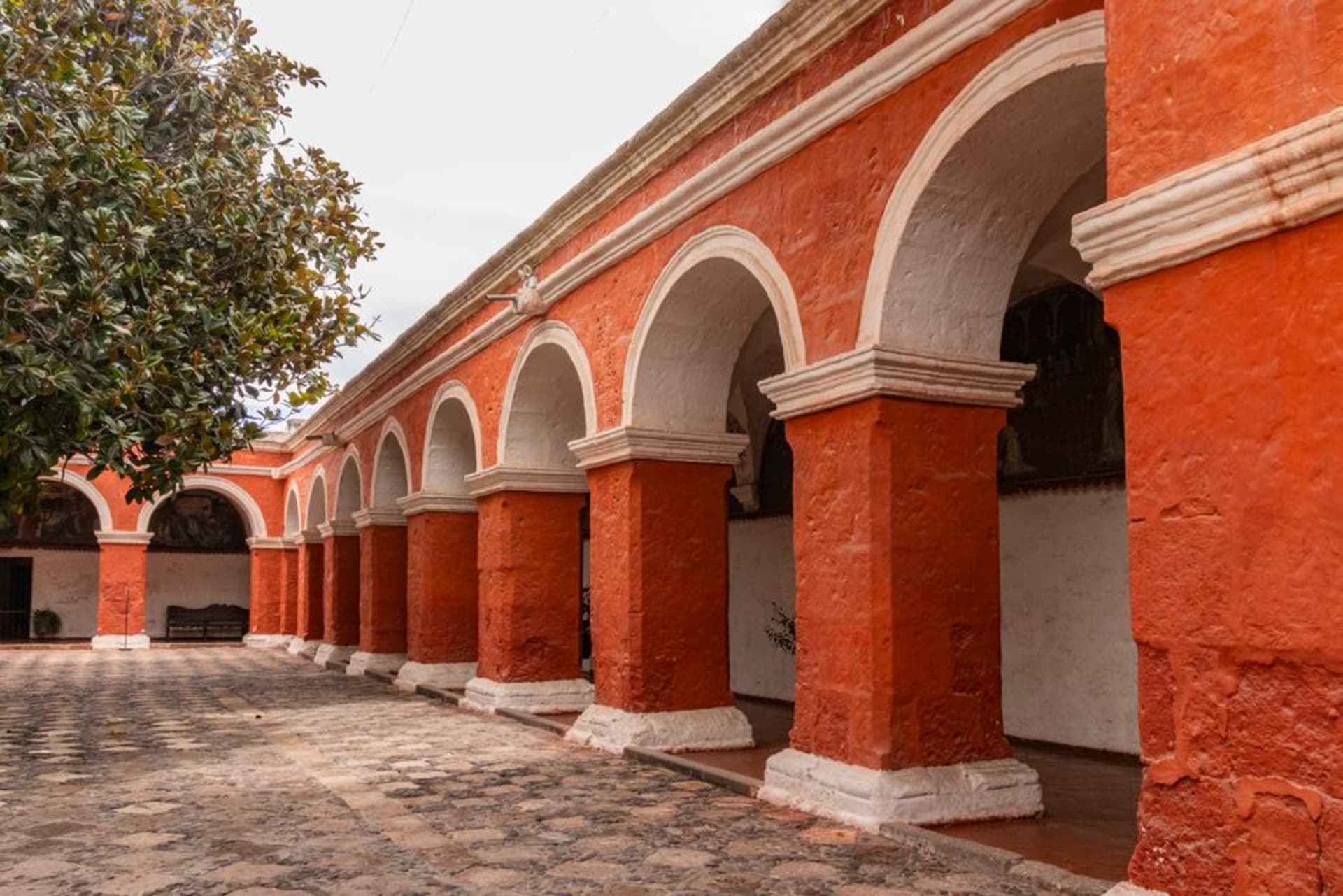 The massive pale stone facade of the Ex-Convento de San Juan Bautista in Yecapixtla, its crenellated roofline visible above market stalls and smoke