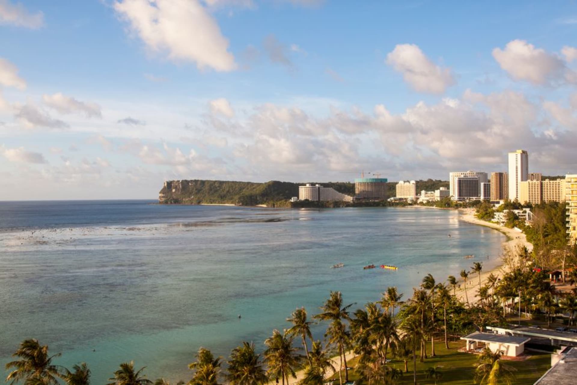 Curved white sand beach and high-rise resort hotels lining Tumon Bay in Guam