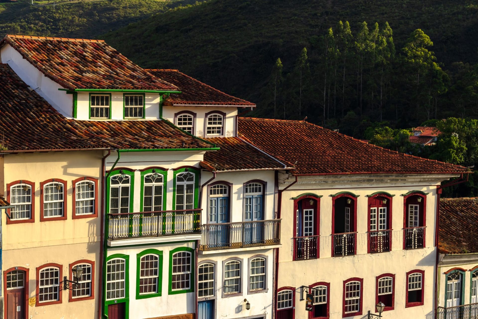 Vue panoramique des toits coloniaux et des clochers d'Ouro Preto se dressant sur des collines vertes sous un ciel bleu dégagé