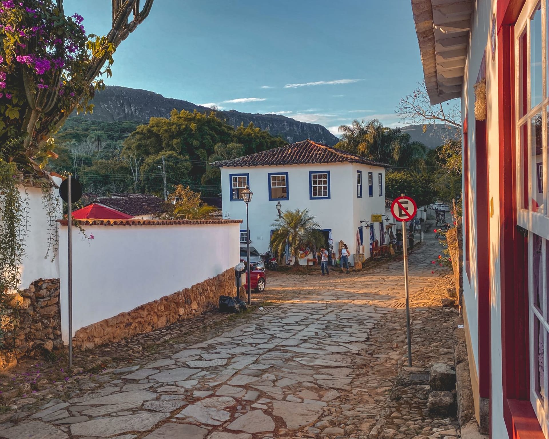 Whitewashed colonial facades and a baroque church tower in Tiradentes seen along a quiet cobblestone street at golden hour
