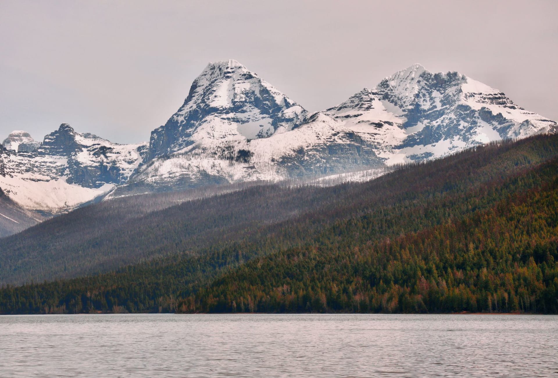 Le lac Two Medicine reflétant des pics calcaires dentelés et un ciel d'orage sur le versant est reculé de Glacier
