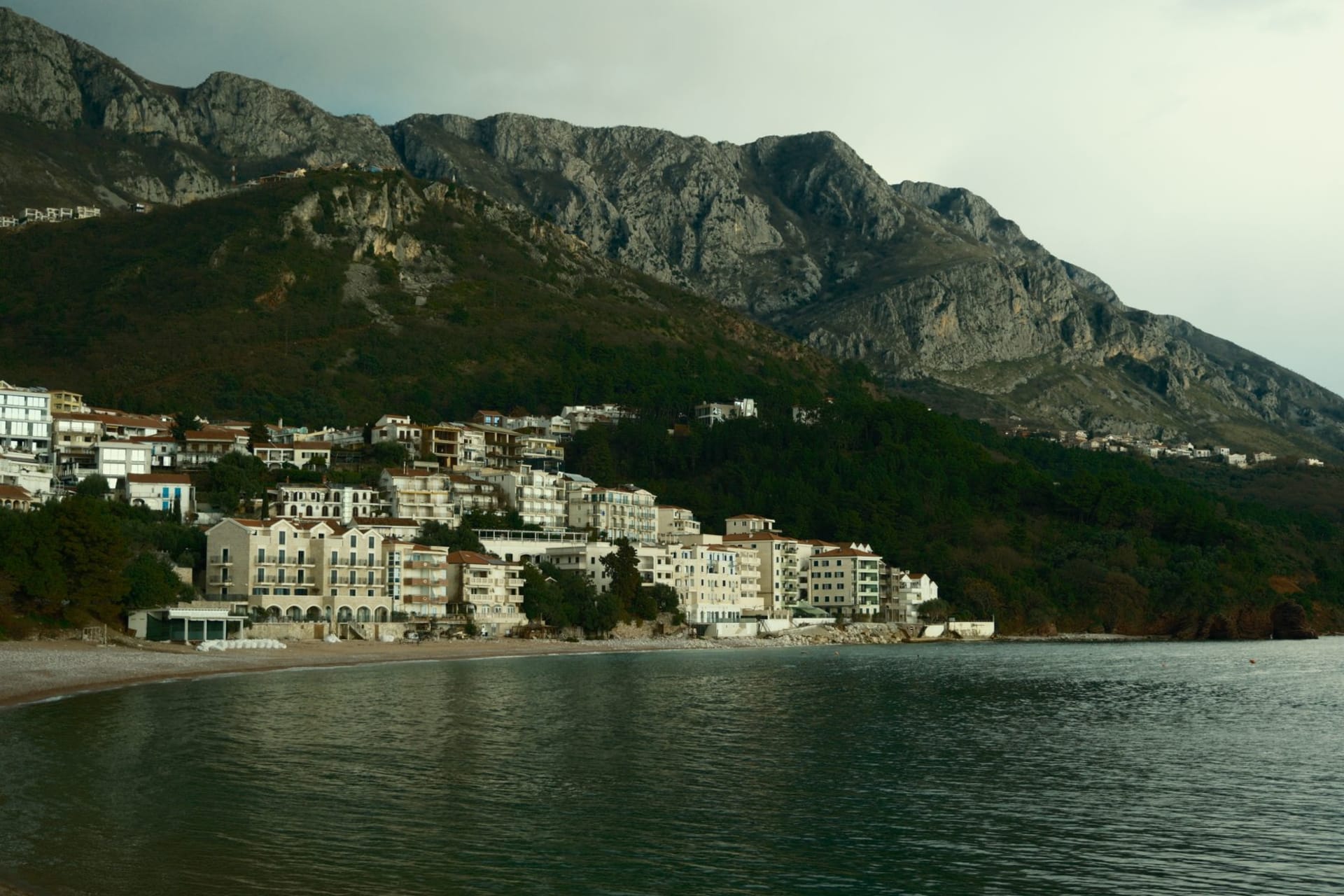 Ulcinj's castle town on its rocky promontory at sunset, medieval walls above the sea, a minaret rising among the rooftops