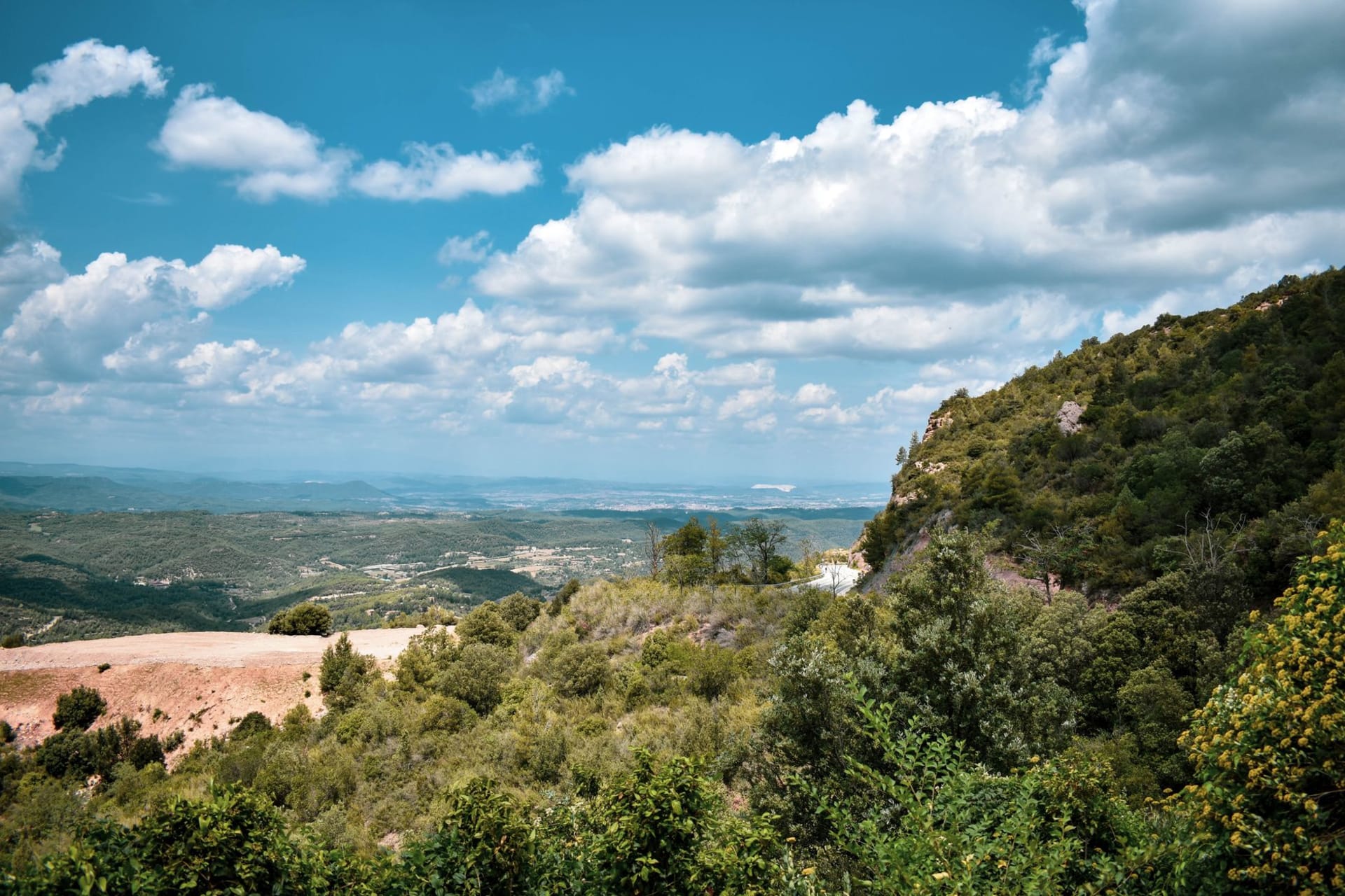 View from Jack Boy Hill Montserrat — exclusion zone ash field and Plymouth's buried rooftops visible below, the sea glittering on the horizon