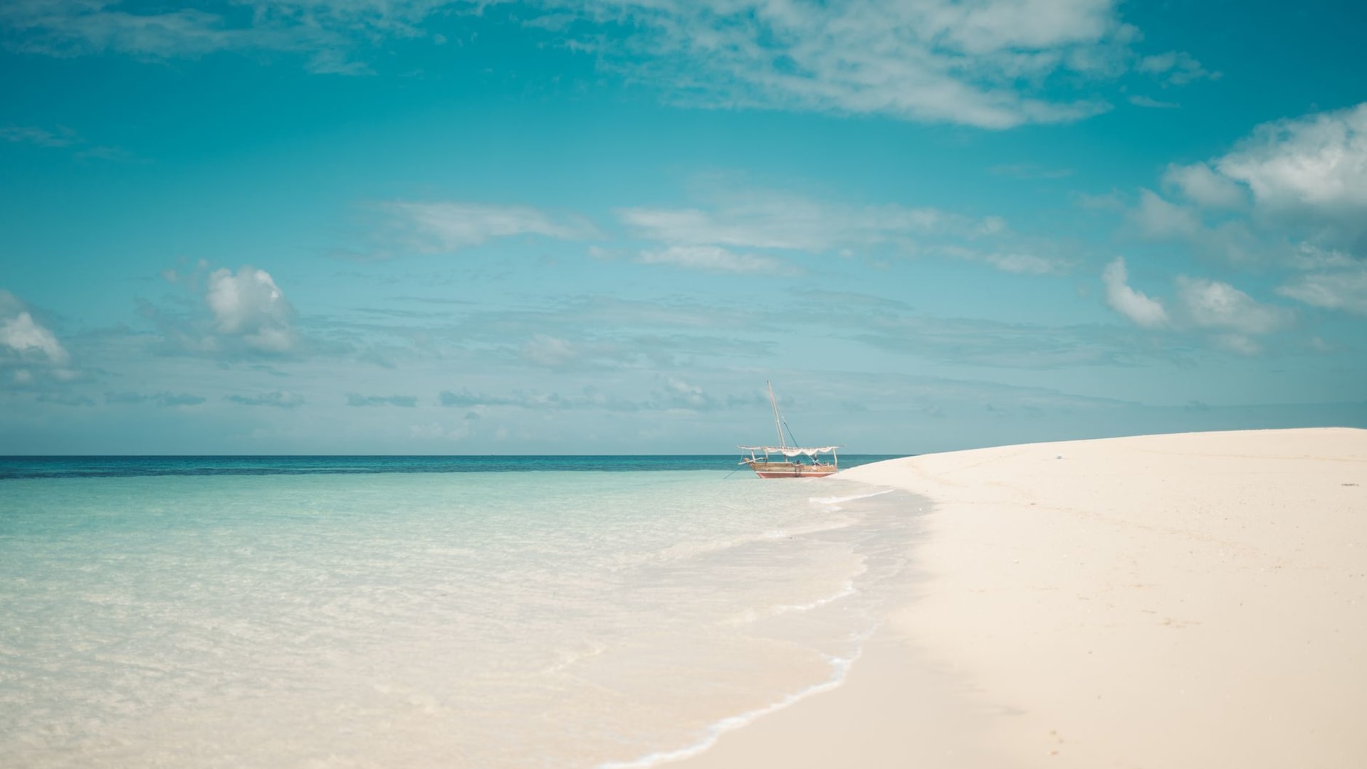 Traditional dhows silhouetted against an orange sky at dusk on Pemba Bay