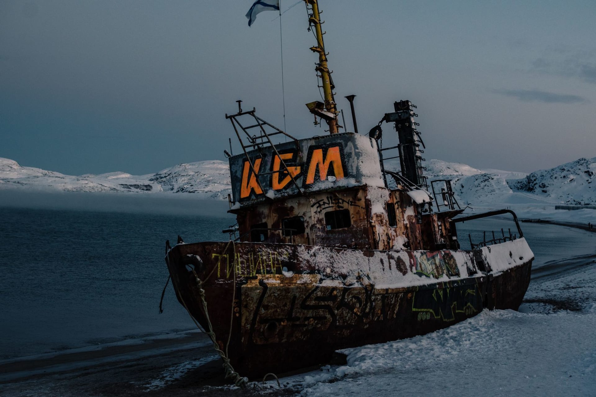 Kandalaksha Bay on the White Sea in winter — pack ice stretching to forested shores, a pale sky above, seabirds in the middle distance