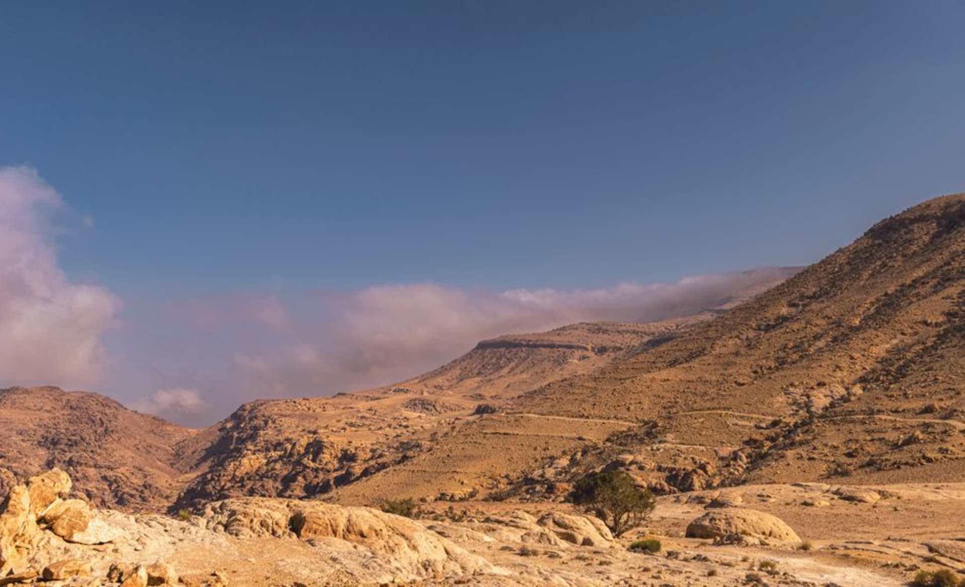 Los muros y torres en ruinas del castillo de Shobak de pie solos sobre una colina árida bajo un cielo amplio, las colinas desérticas vacías en todas direcciones