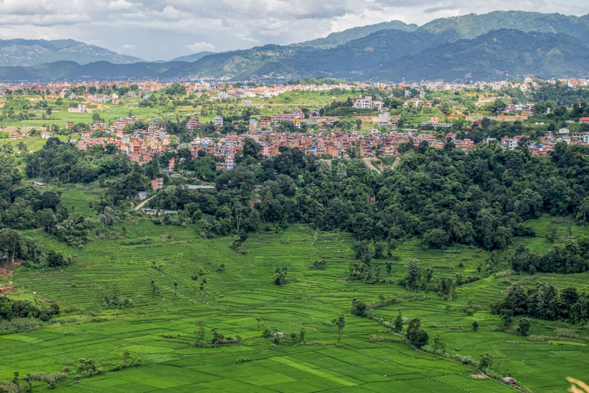 Terraced stone houses of Chhomrong village descending a steep hillside with Annapurna South visible in the distance