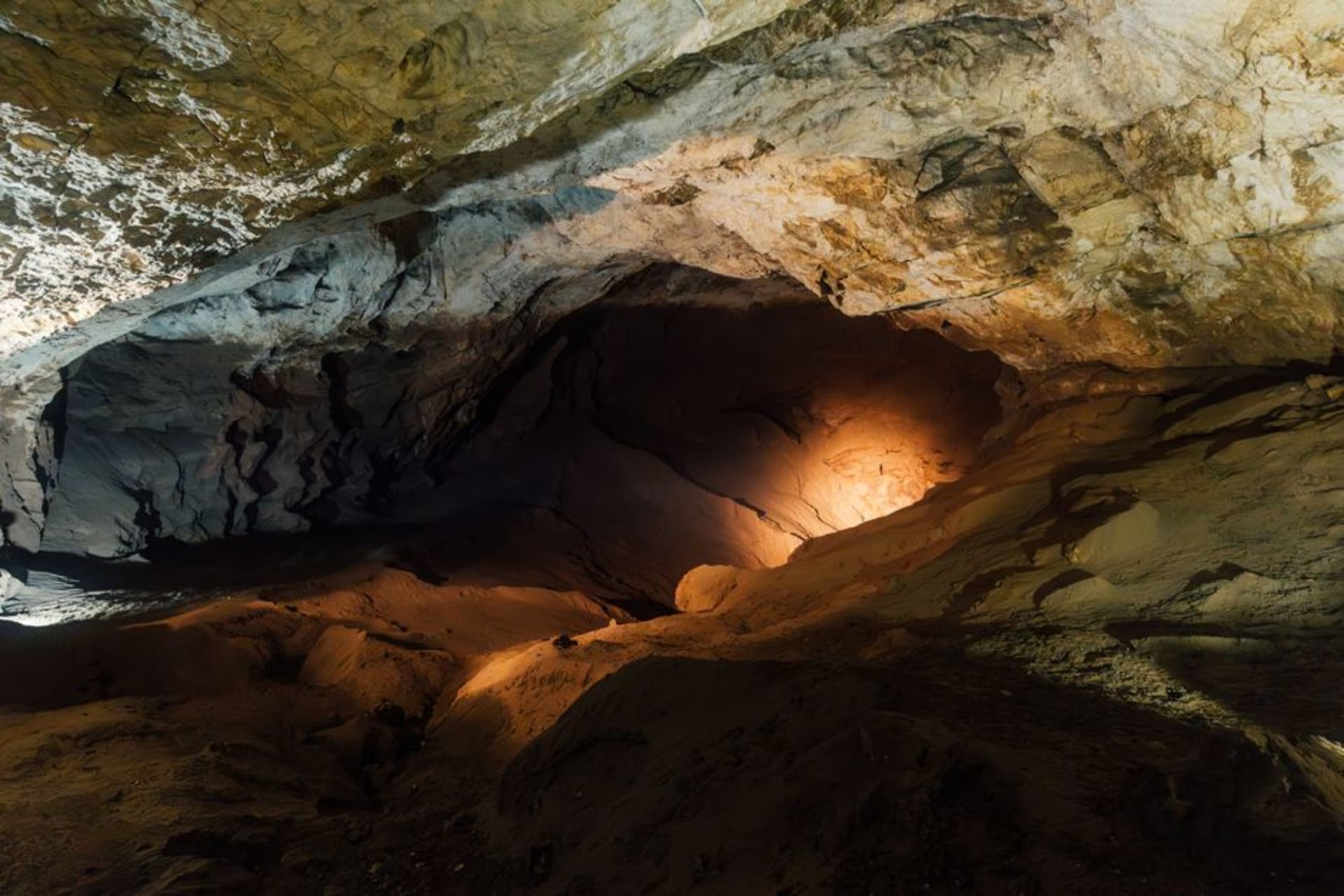 Passage calcaire humide à l'intérieur de la grotte de Gupteshwor près de Pokhara, éclairé par des chapelets d'ampoules nues descendant vers une chambre souterraine