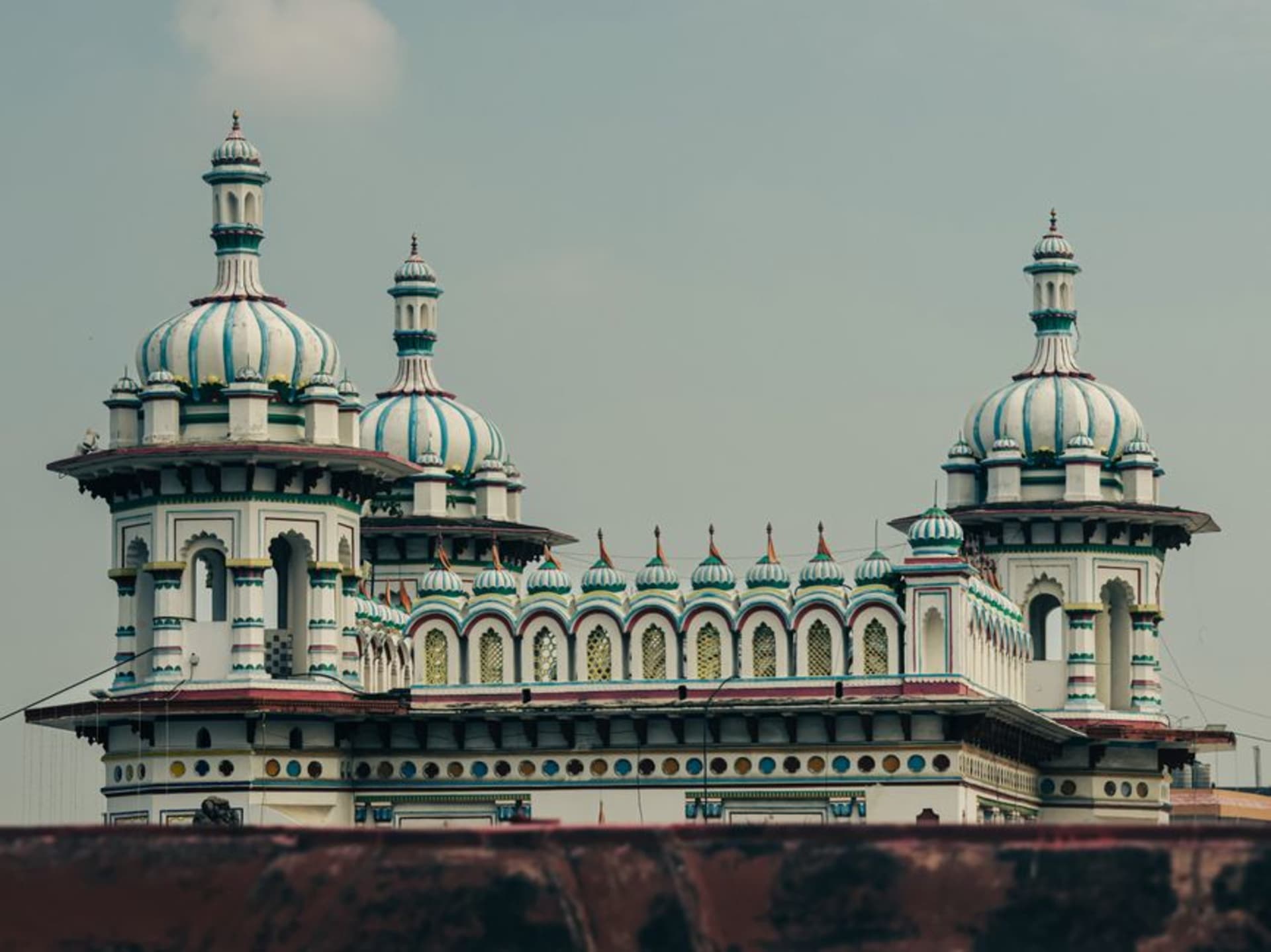 The white and pink domes of the Janaki Mandir temple in Janakpur reflected in the temple pond at dusk