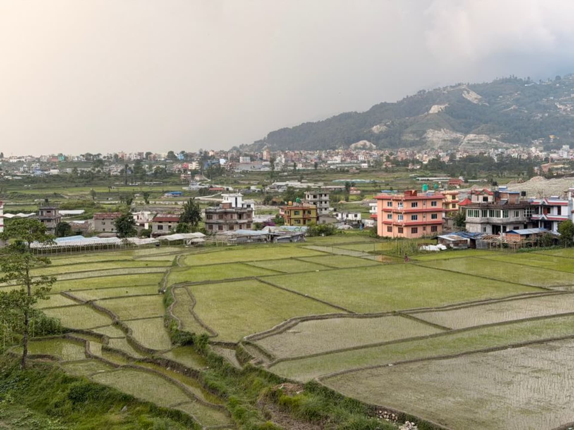 El perfil urbano de Kirtipur en lo alto de la colina, con casas de ladrillo rojo y techos de templos pagoda contra un suave cielo de tarde, en el borde del valle de Katmandú