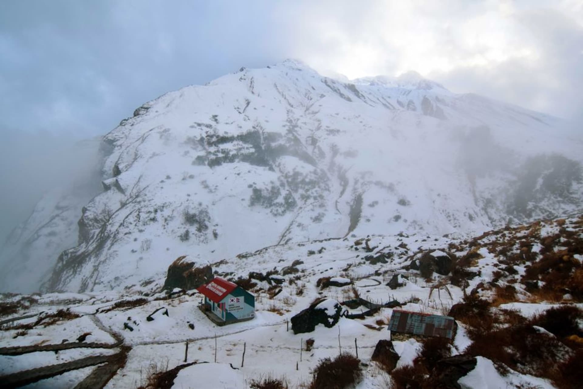 La cumbre piramidal de granito del Makalu elevándose sobre el valle pedregoso de Barun, con un pequeño campamento de trekking visible en primer plano