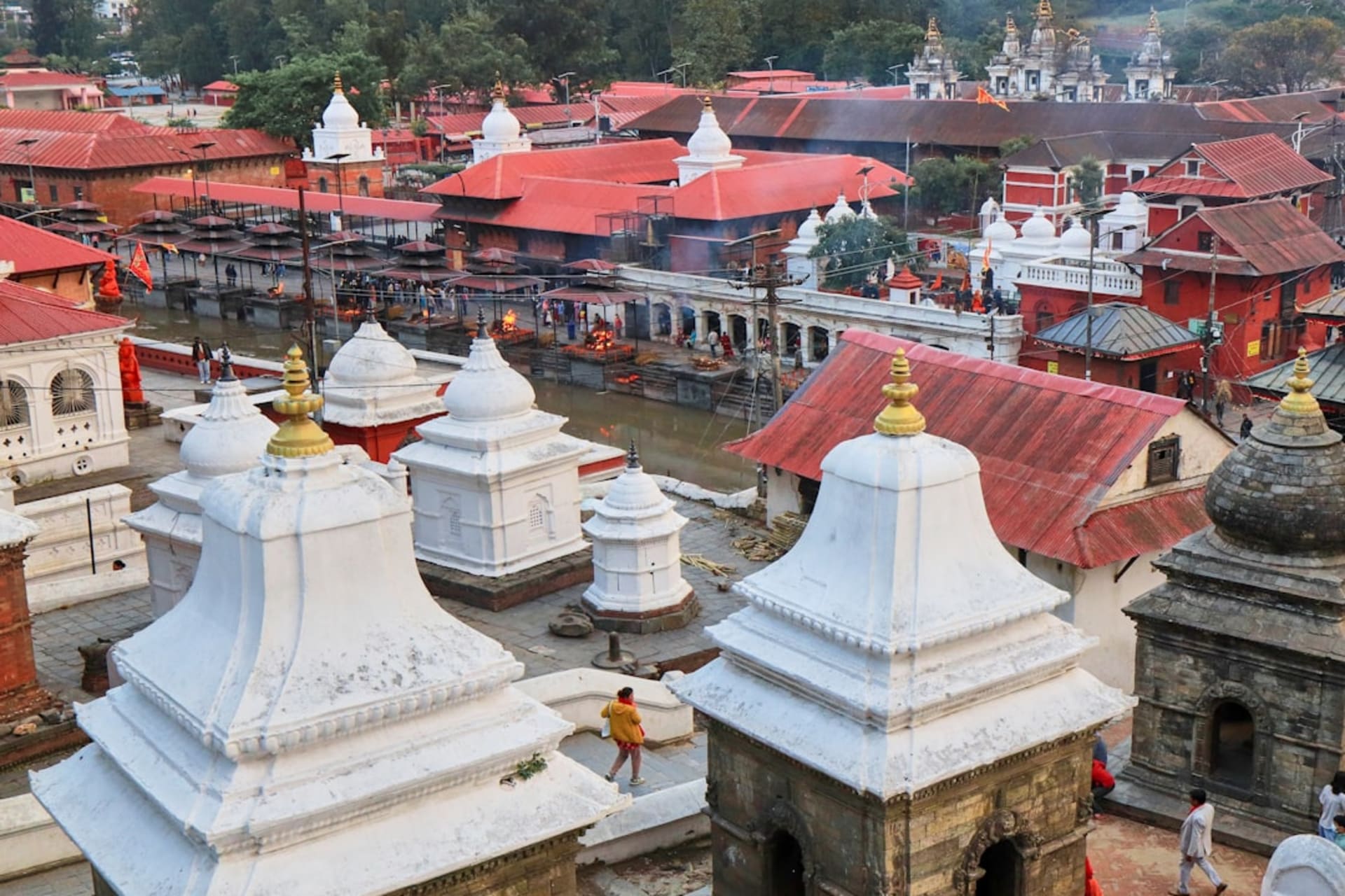 Pilgrims and prayer flags at the wind-battered Pathibhara Devi shrine on a high open ridge with layered mountain ranges receding into the distance