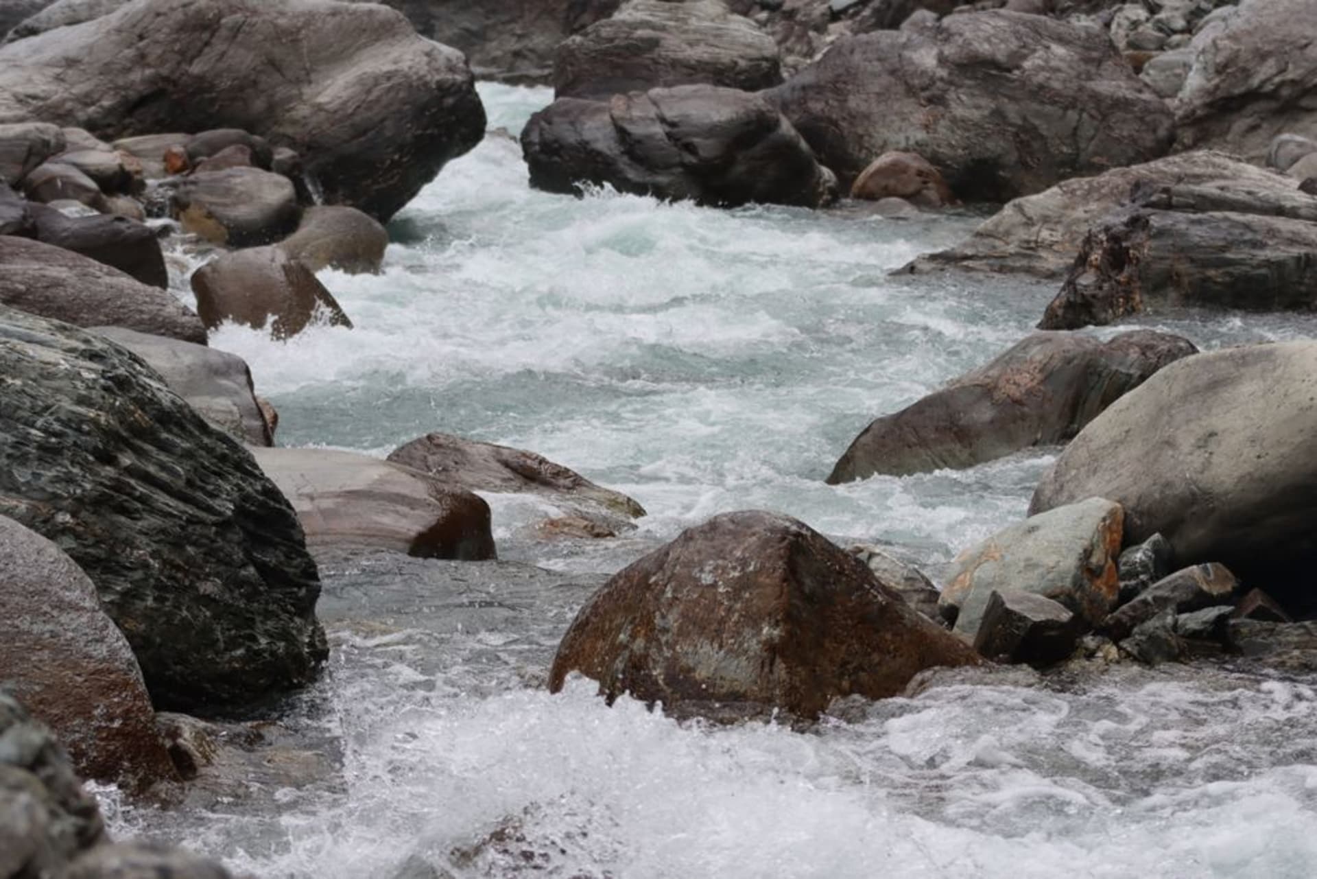 Bassins de sources chaudes naturelles fumants, aménagés dans la pierre au village de Tatopani, avec les parois de la vallée de la Kali Gandaki s'élevant derrière