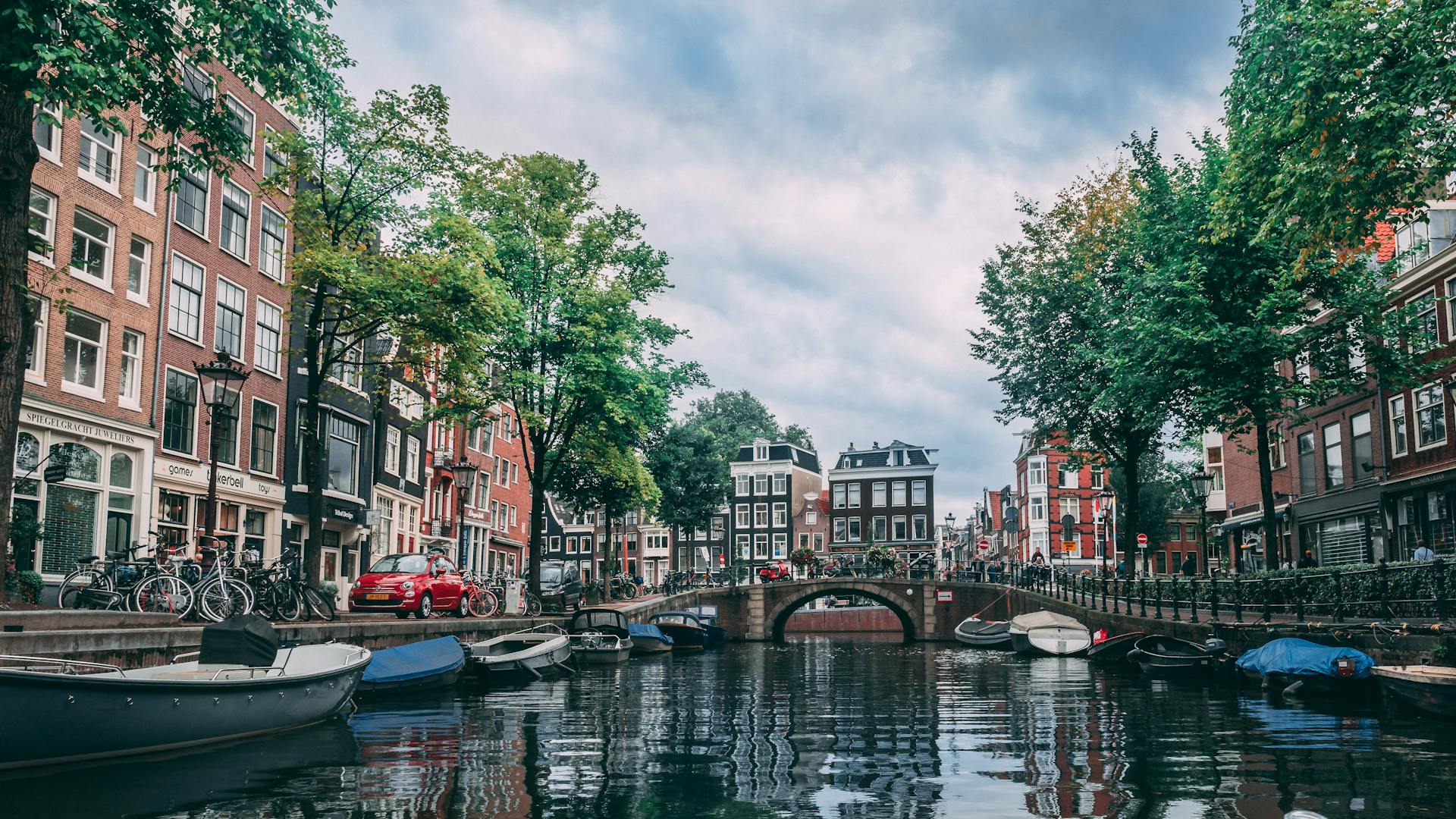 A tree-lined canal in Delft with the Nieuwe Kerk tower rising in the background
