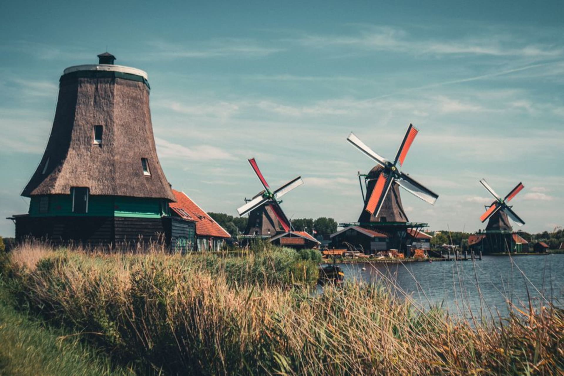 Row of green wooden windmills along the Zaan River at Zaanse Schans
