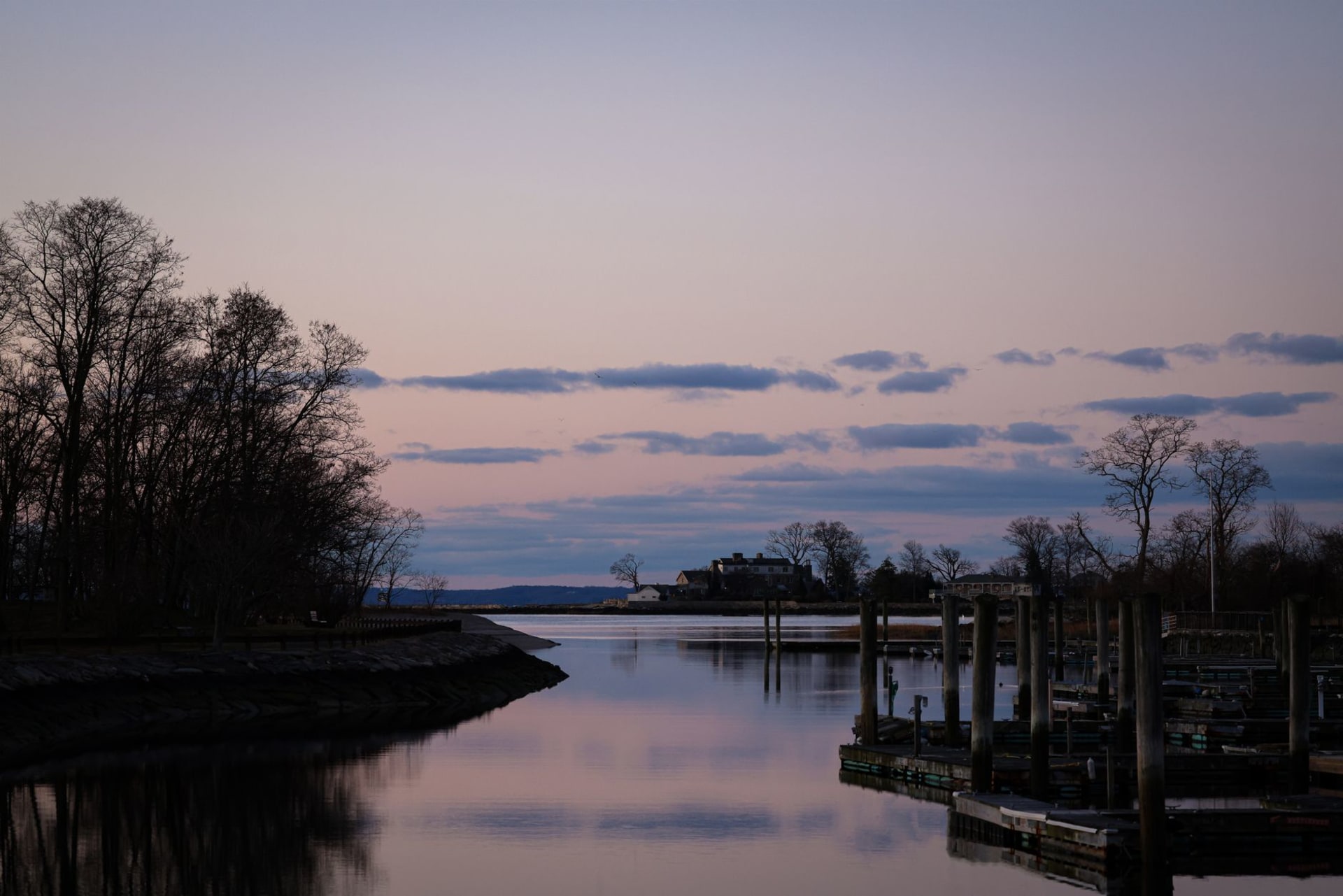 The tall ship Charles W. Morgan at Mystic Seaport, its three masts rising above the historic shipyard buildings at dusk