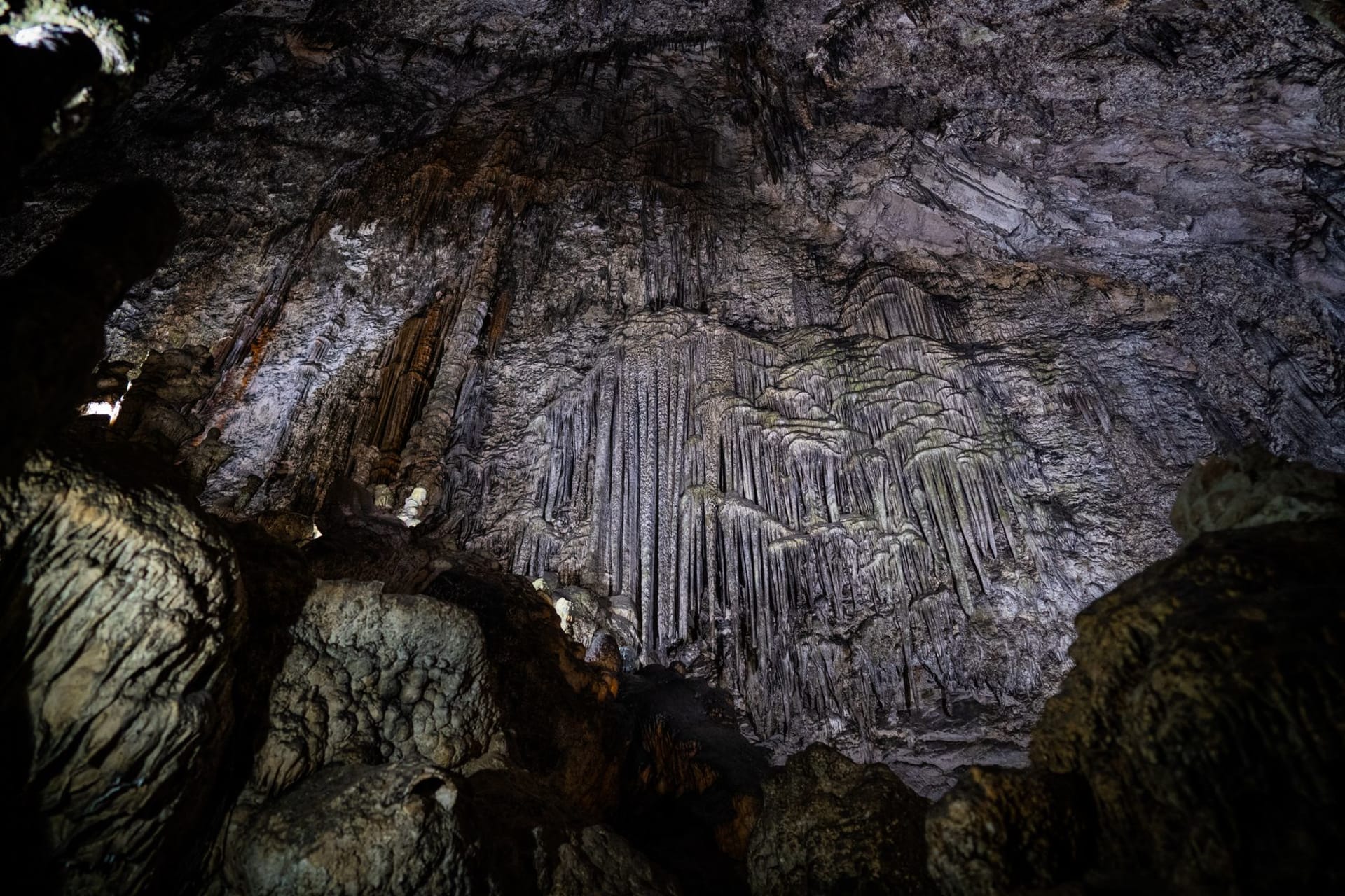 The vast underground Big Room of Carlsbad Caverns illuminated in amber and blue, stalactites hanging from the ceiling