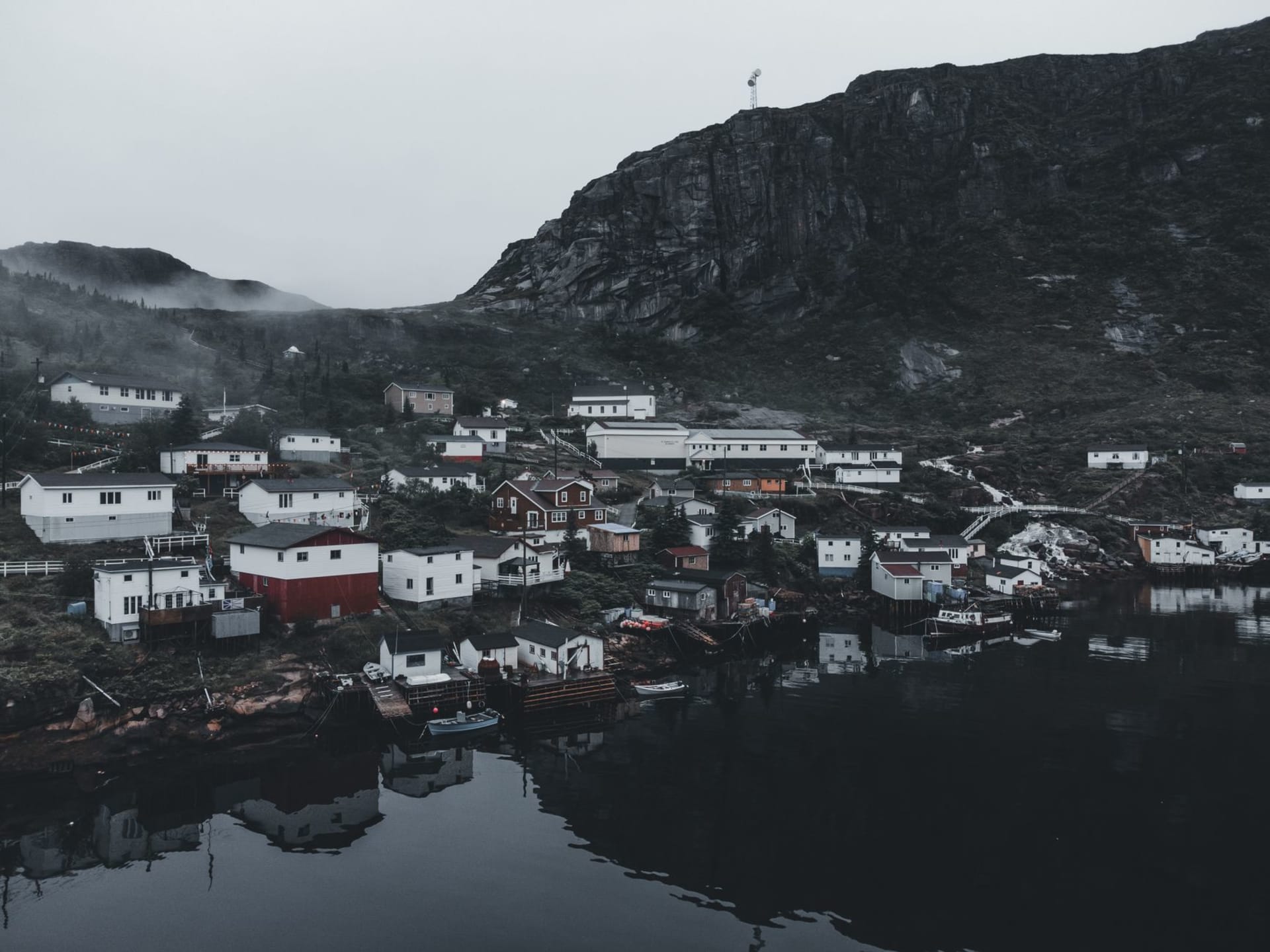 L'anguleux Fogo Island Inn blanc sur pilotis au-dessus du rivage rocheux de l'île Fogo, Terre-Neuve, avec de la glace de mer au loin