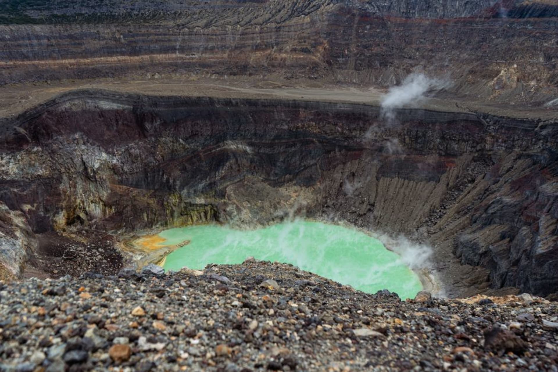 El lago de cráter circular de Apoyeque visto desde su borde boscoso, agua azul-verdosa profunda rodeada de escarpadas paredes volcánicas
