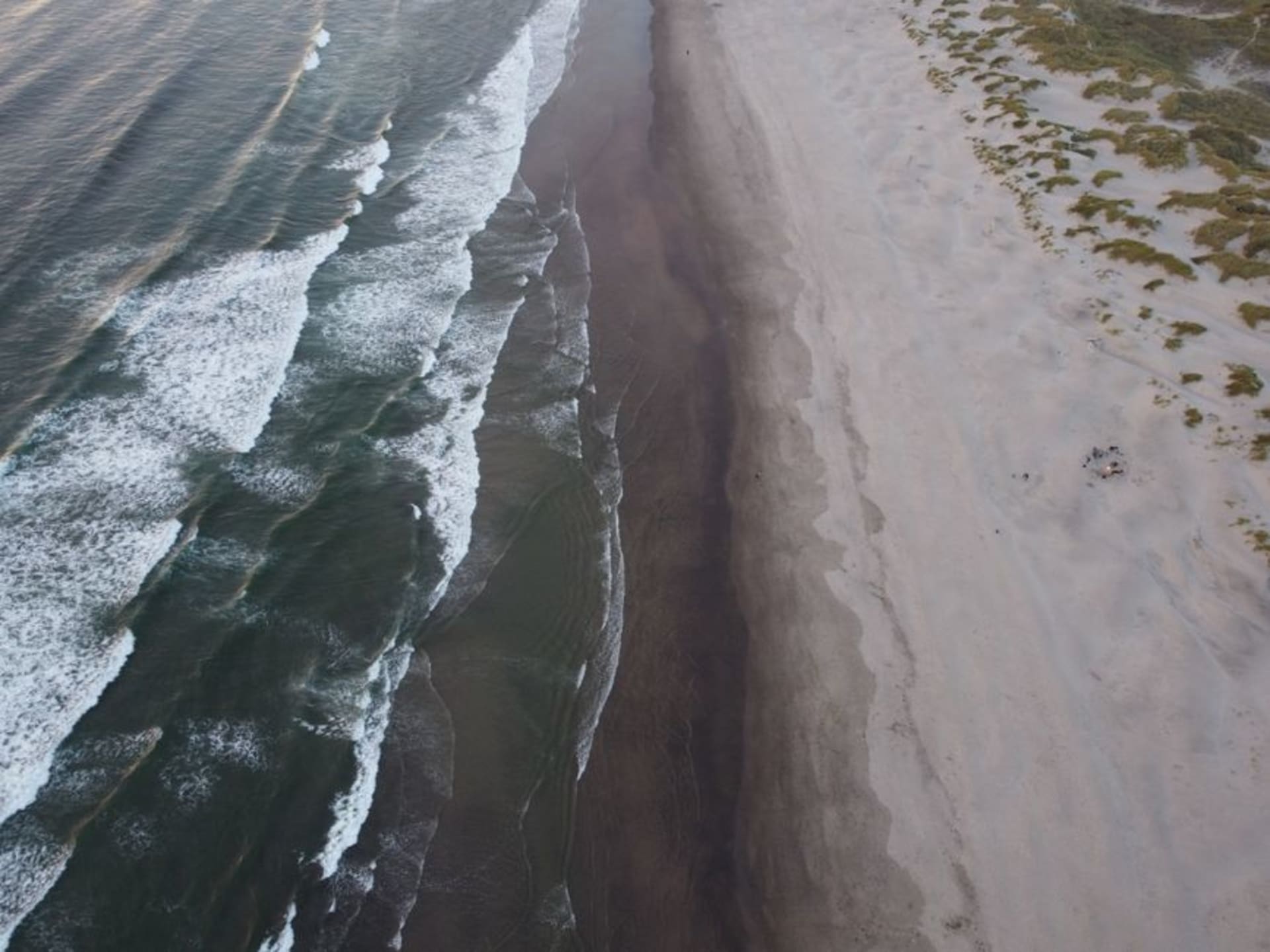 Long empty stretch of sand at Playa Hermosa with waves rolling in