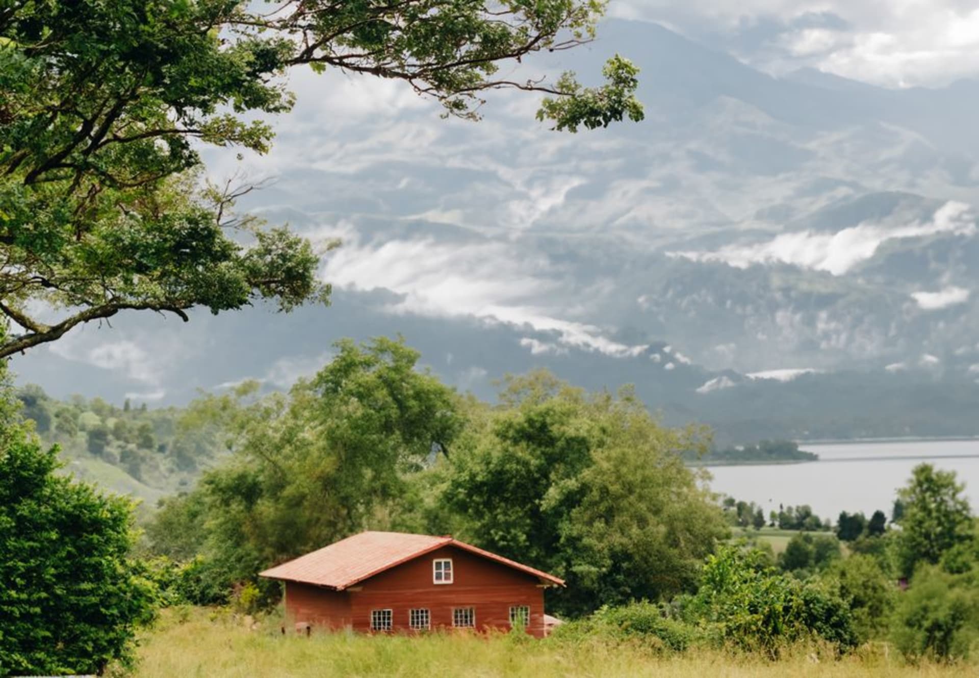 Un chalet de entramado de madera con techo de pendiente pronunciada en el ecolodge Selva Negra, rodeado de bosque nuboso y un lago en calma que refleja la estructura