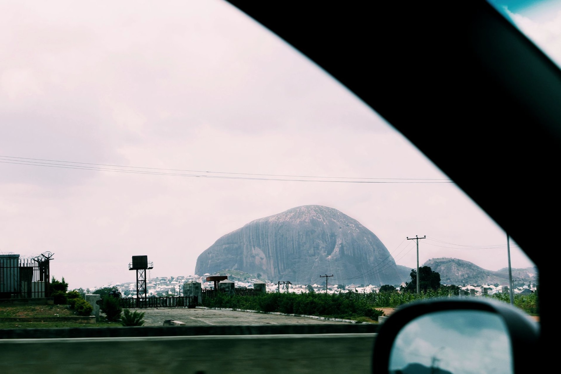 Zuma Rock looming over the road near Suleja, its dark volcanic face rising abruptly from the flat savannah landscape outside Abuja