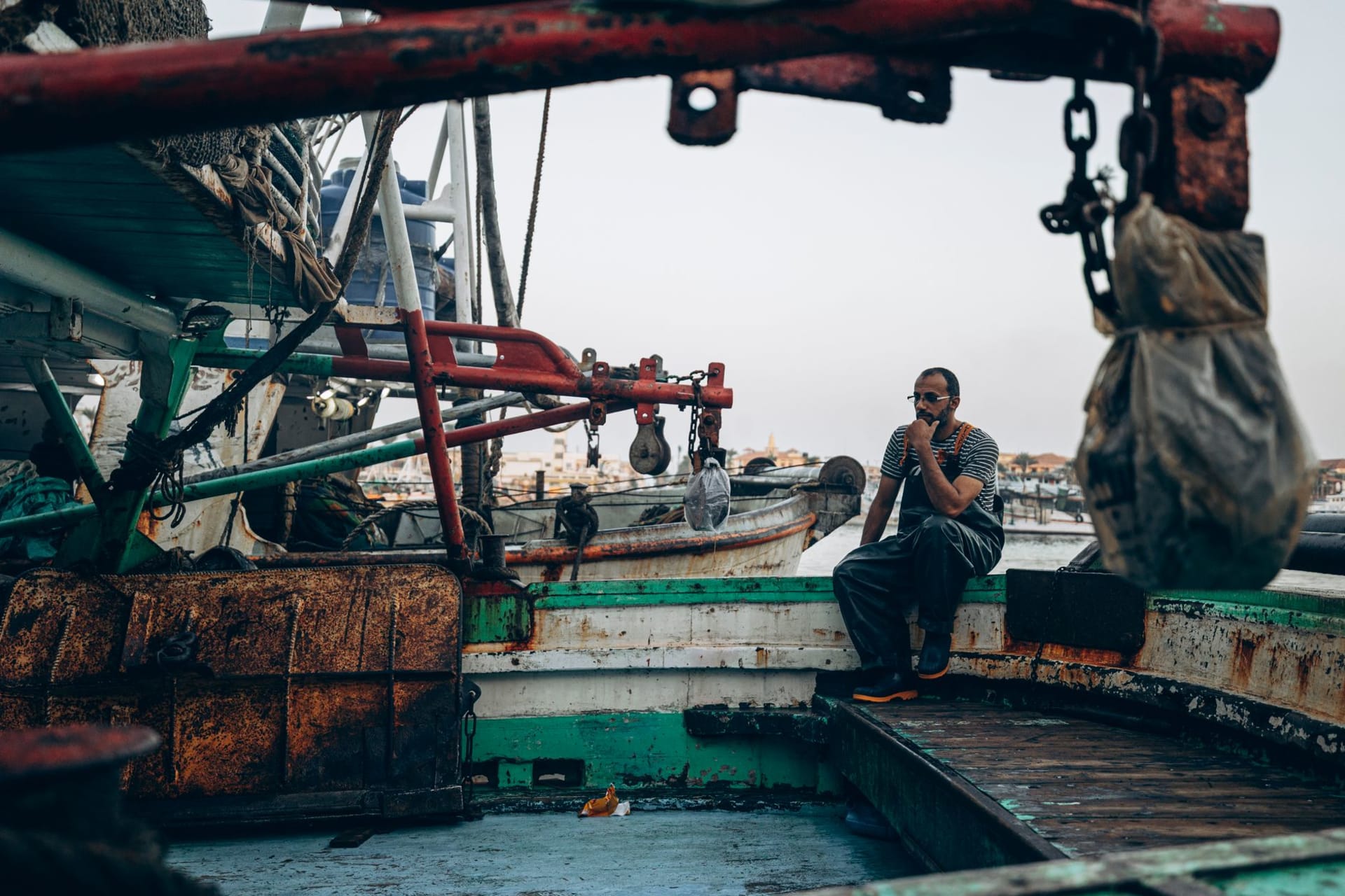 Colorful fishing boats moored along the Nile at Damietta at sunrise, their reflections wavering in the brown current