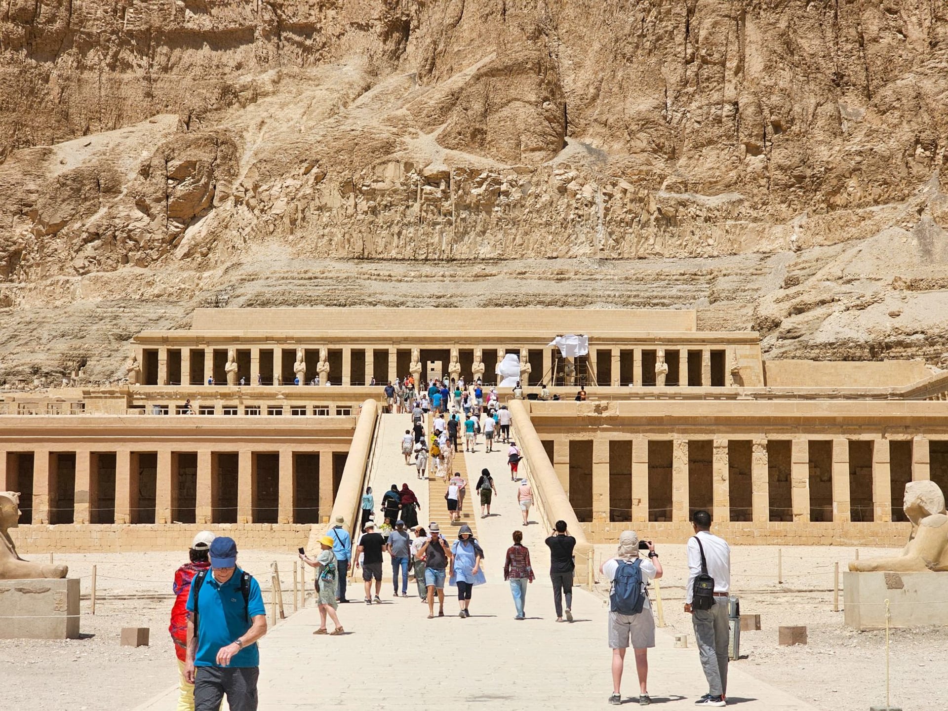 The arid golden limestone cliffs of the Valley of the Kings under a cloudless blue sky, tomb entrances visible in the rock face