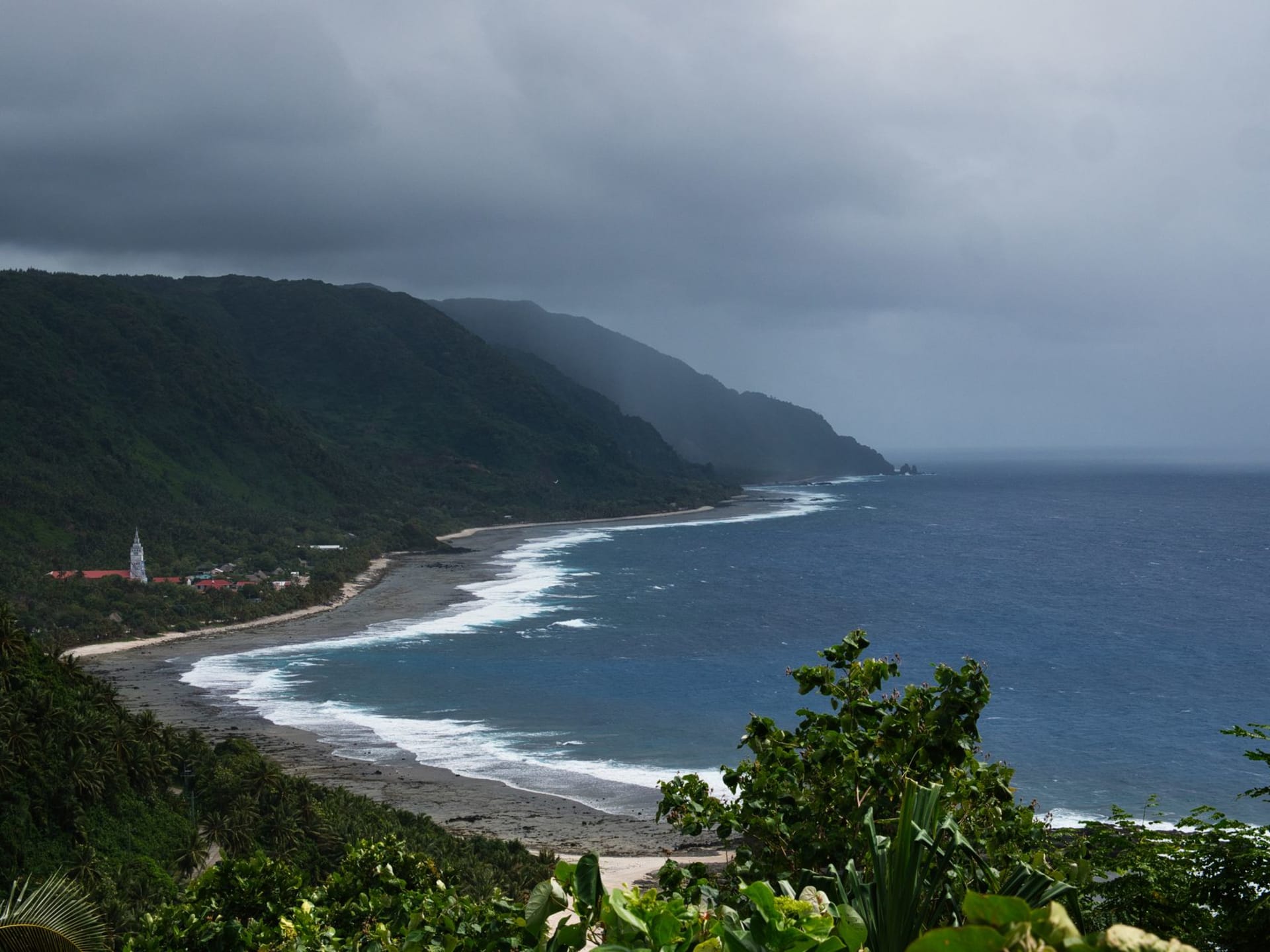 Hakupu village church surrounded by tropical vegetation on Niue's south coast, morning mist in the trees