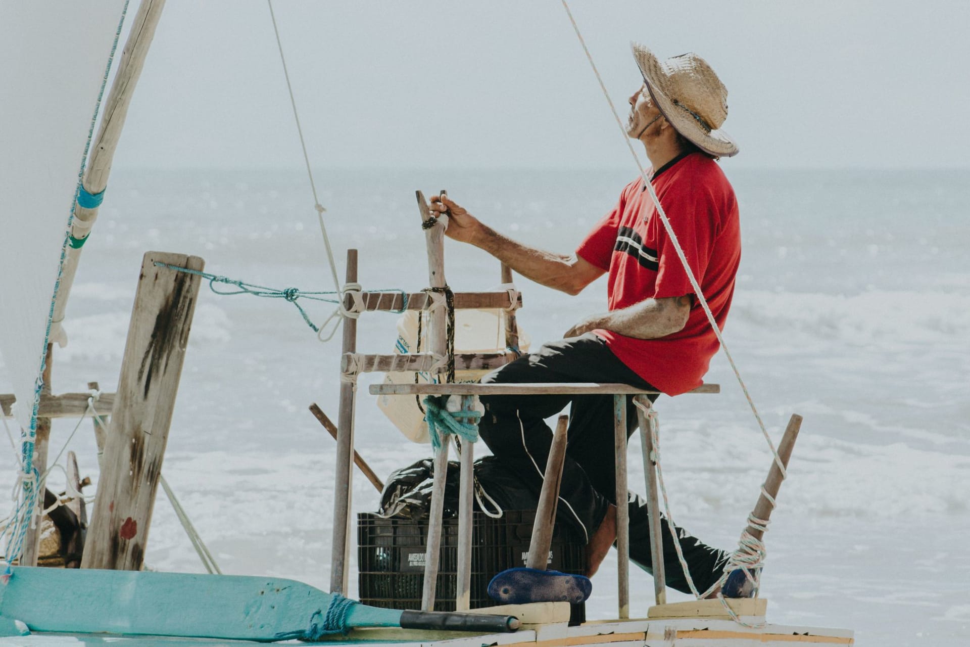 The red and ochre falésias of Canoa Quebrada rising dramatically from a white sand beach, the cliffs wind-carved into organic shapes, a jangada with a white sail visible at the water's edge