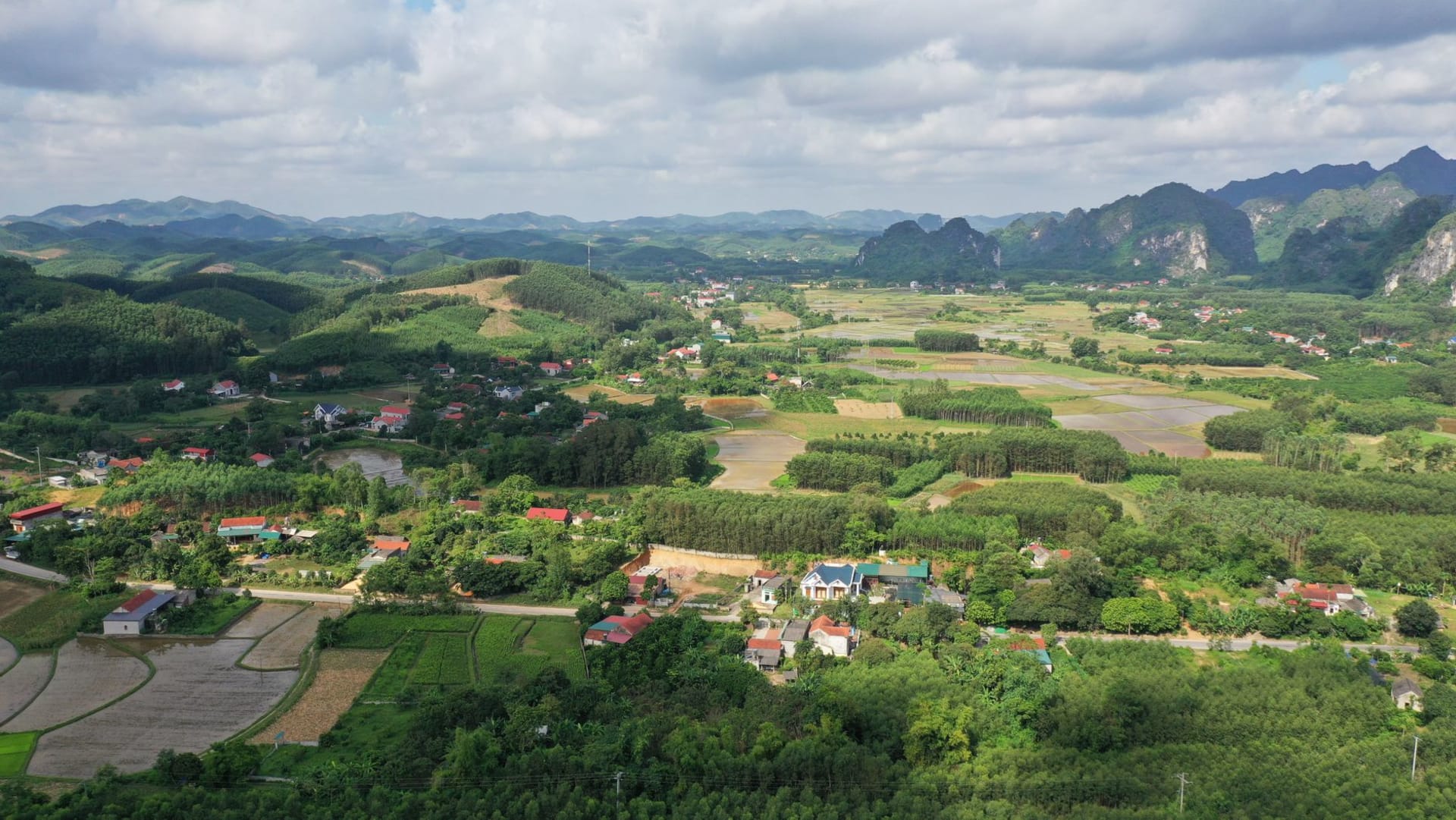 The Lũng Cú flag tower on the summit of Dragon Mountain, Vietnam's national flag flying against a clear sky, karst peaks extending to the horizon