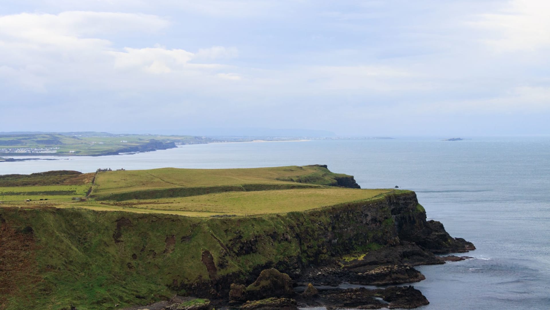 Rathlin Island's West Lighthouse perched on white chalk cliffs above the blue Atlantic, puffins visible on the ledges below