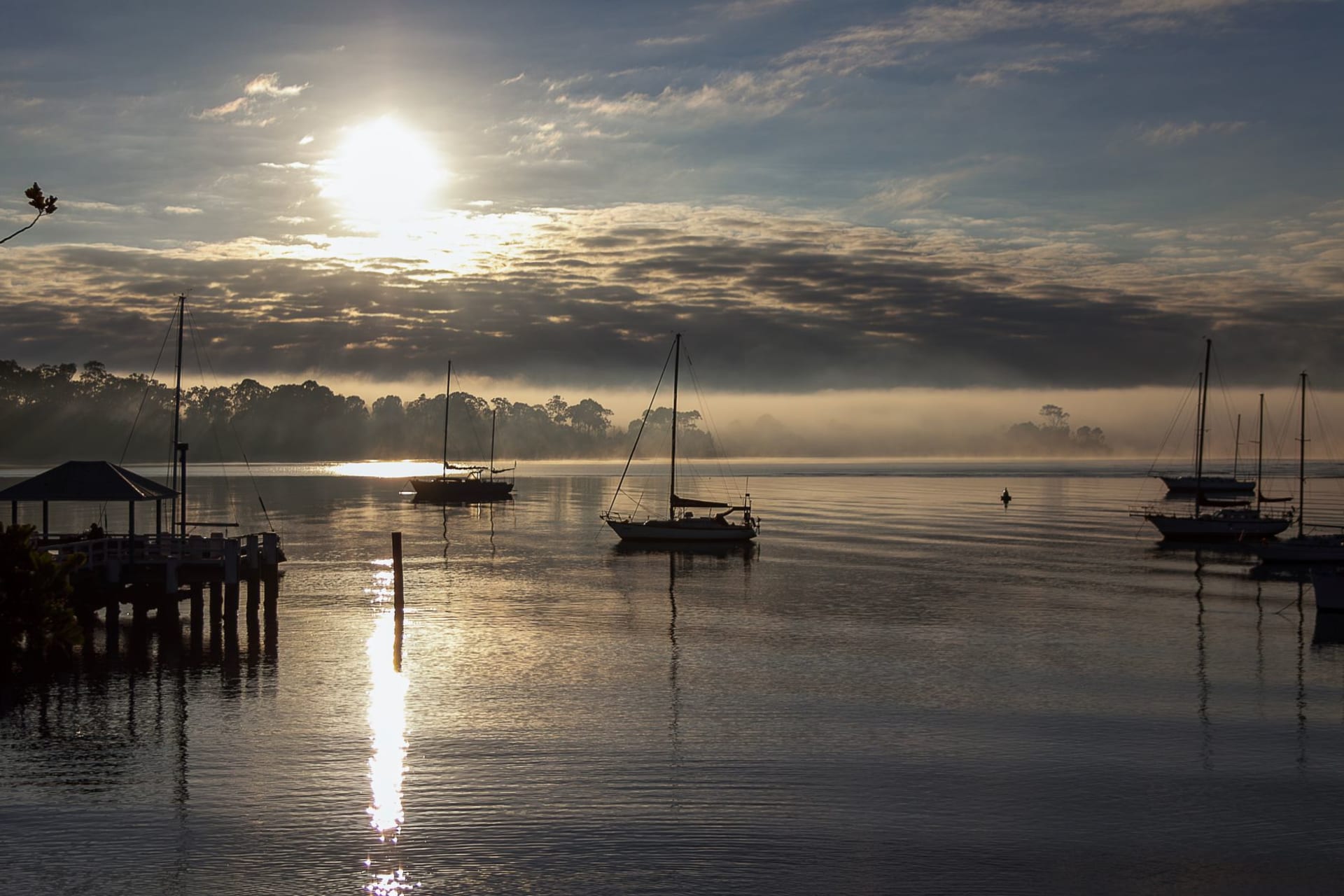 Three white historic churches of Mahone Bay perfectly reflected in the still grey water of the bay on a calm morning