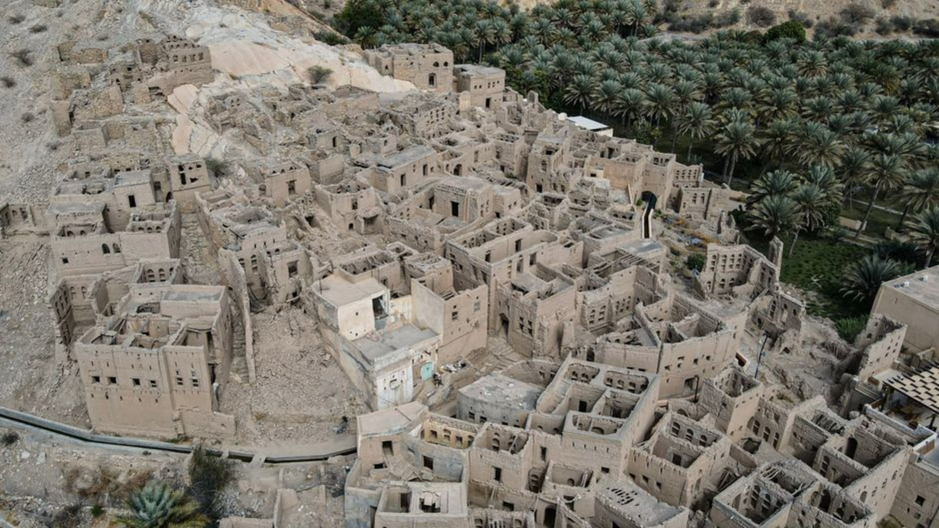 Ancient stone beehive-shaped burial tombs scattered across a barren ridge at the Bat archaeological site, Oman