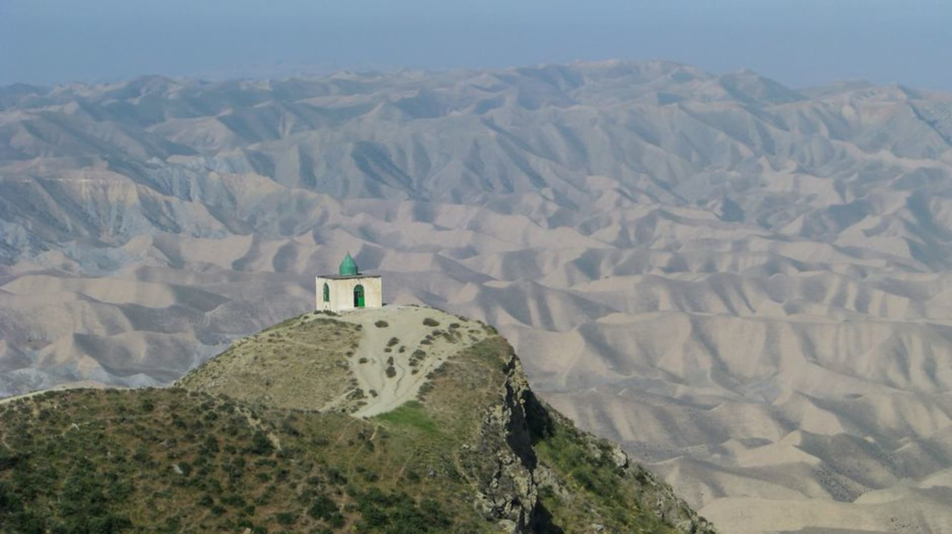 White domed shrine of Nabi Ayoub, the tomb of the prophet Job, on Jebel Itin mountain overlooking misty Dhofar hills, Oman