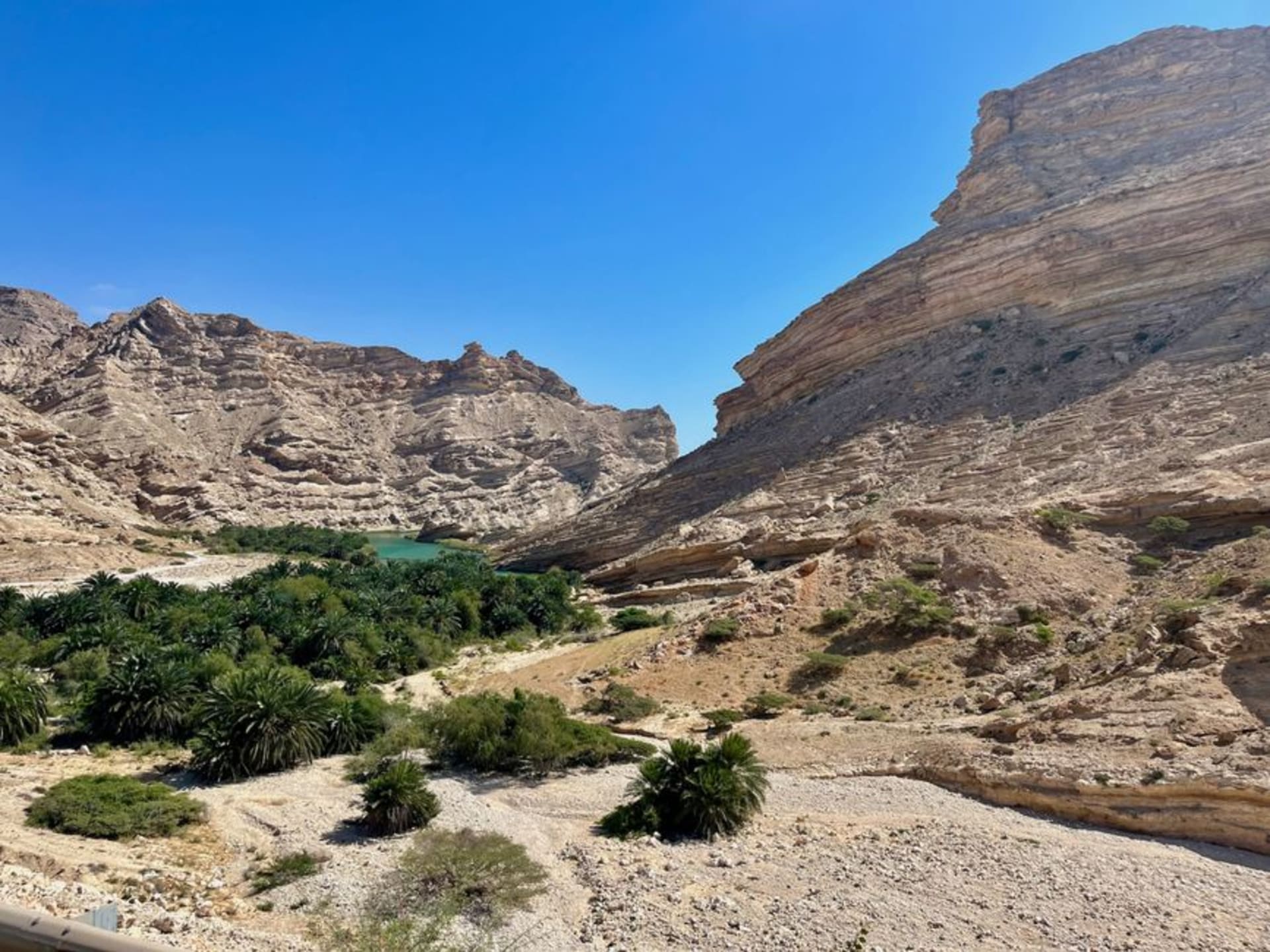 Wadi Darbat canyon lake surrounded by green cliffs during the khareef monsoon in Dhofar, Oman, with small wooden canoes on the water