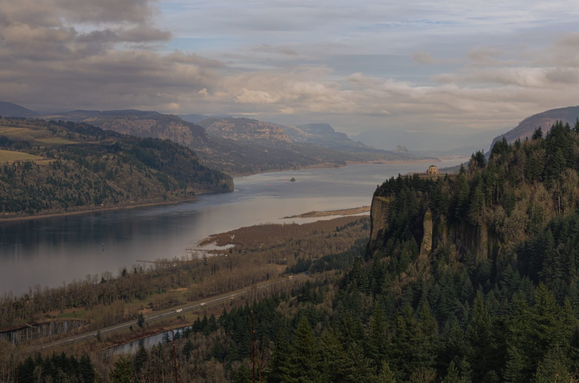 The Columbia River Gorge at sunrise, basalt cliffs rising from the wide river with morning mist in the valleys