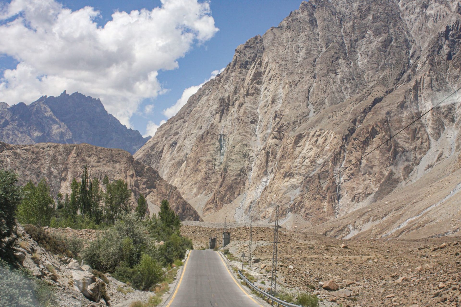 The Khunjerab Pass border marker at 4,693 meters, the vast brown plateau stretching toward the Chinese Pamirs under a deep blue sky
