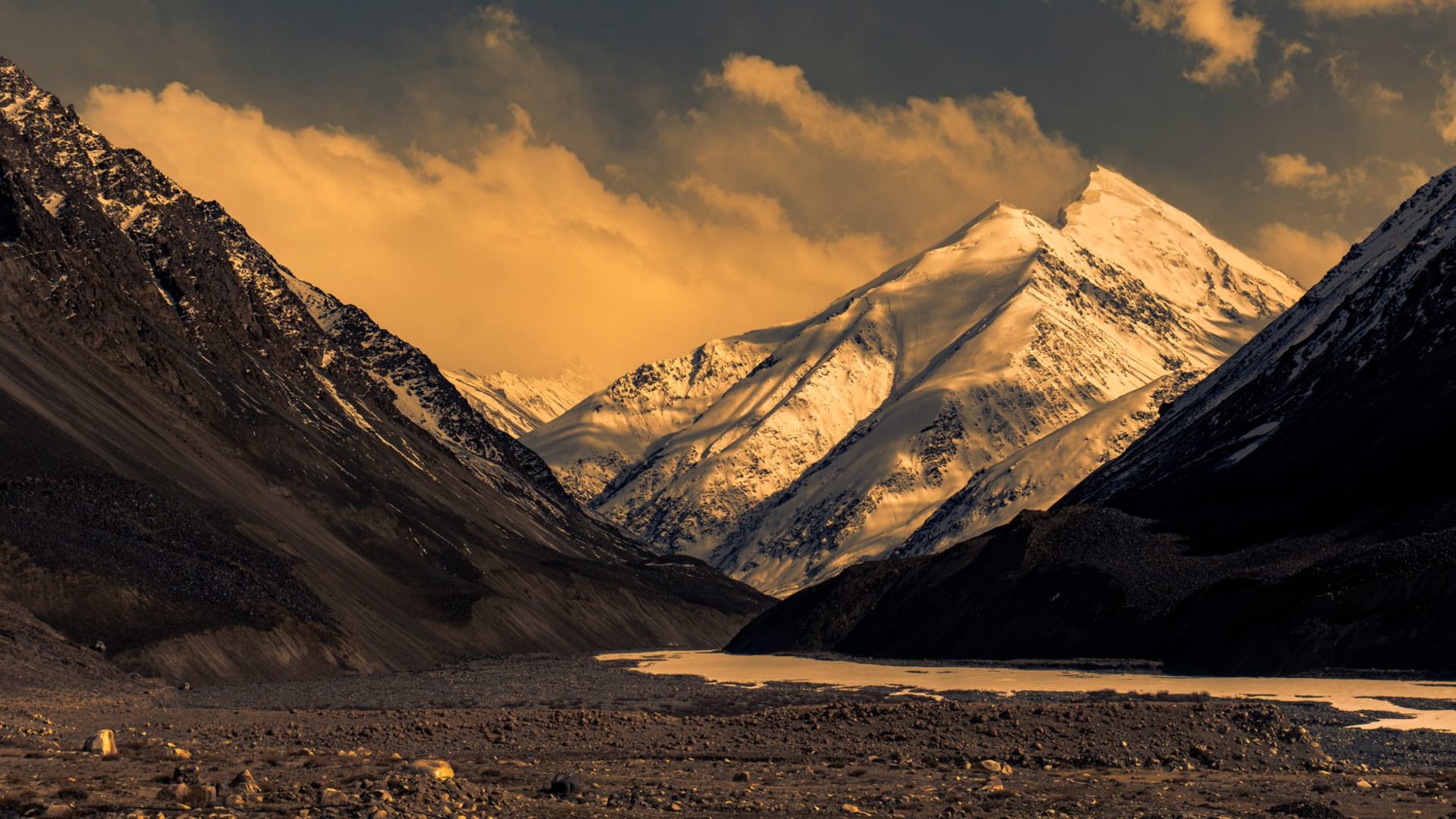 Snow-capped peaks of northern Pakistan blazing orange and purple during a dramatic sunset, Karakoram range in the distance