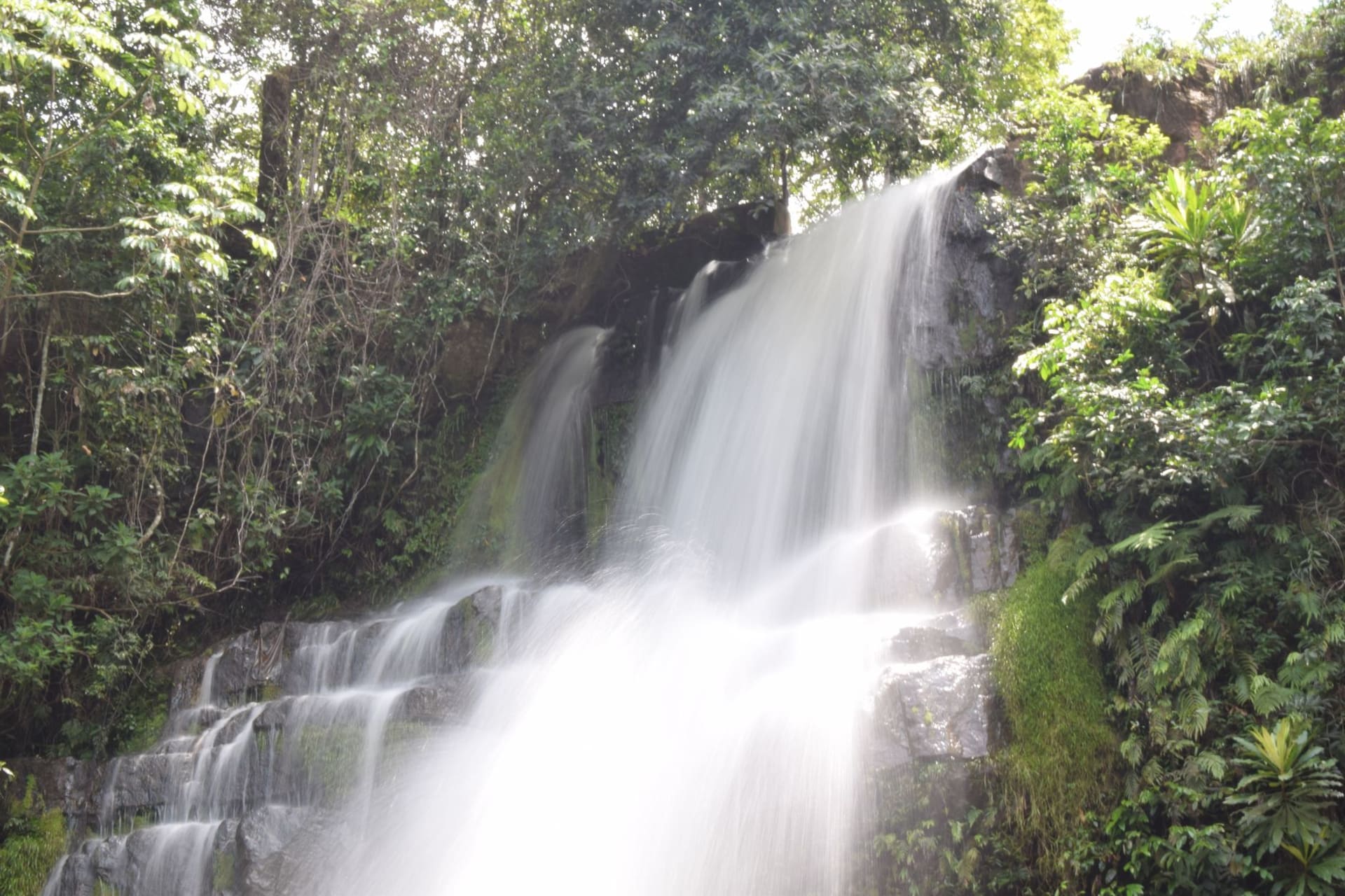 Ngardmau waterfall cascading through dense jungle on Babeldaob island, Palau, mist rising from the pool below