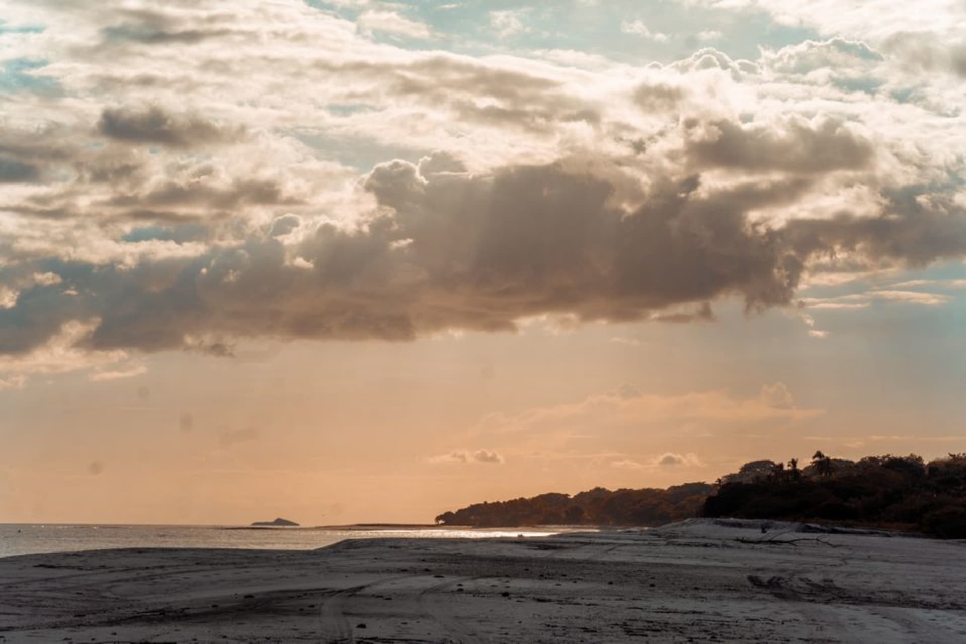 The curved horseshoe bay of Playa Venao with rolling waves and green headlands framing both ends of the beach.