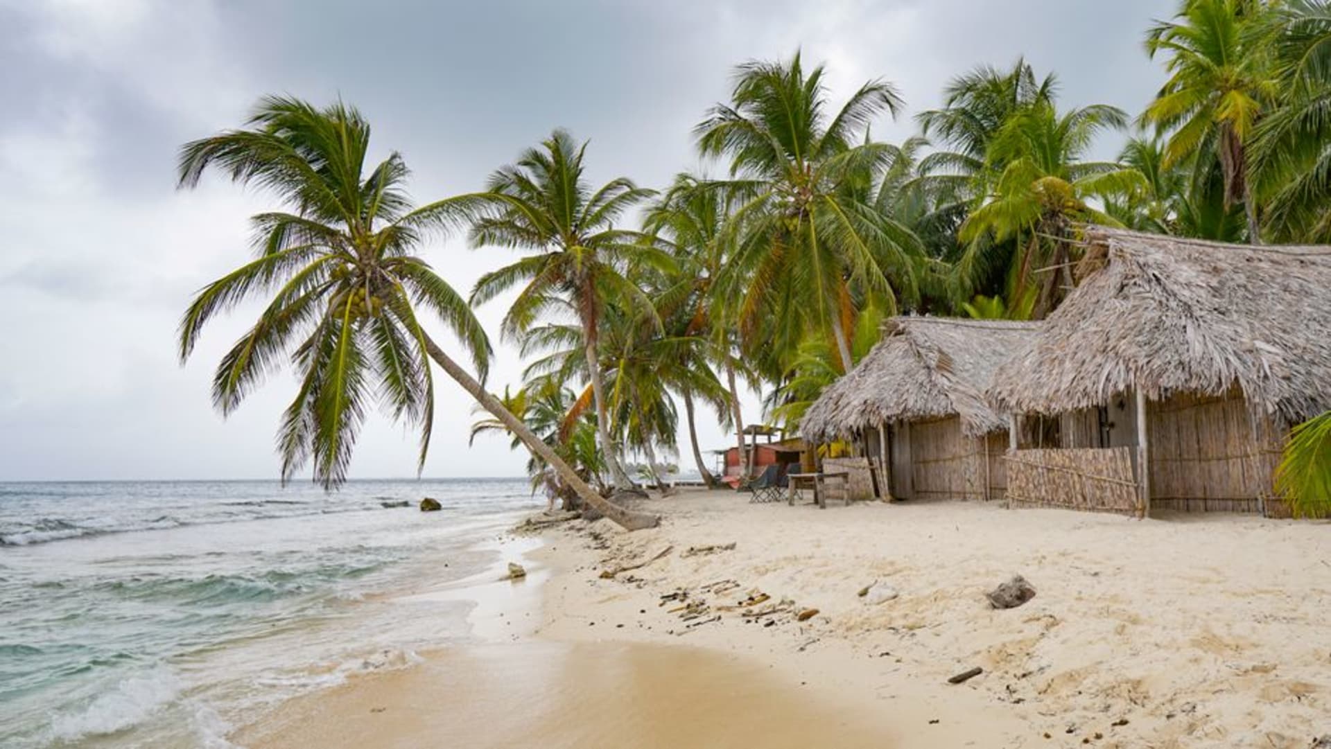 A cluster of tiny palm-covered San Blas islets surrounded by shallow turquoise Caribbean water, seen from above.