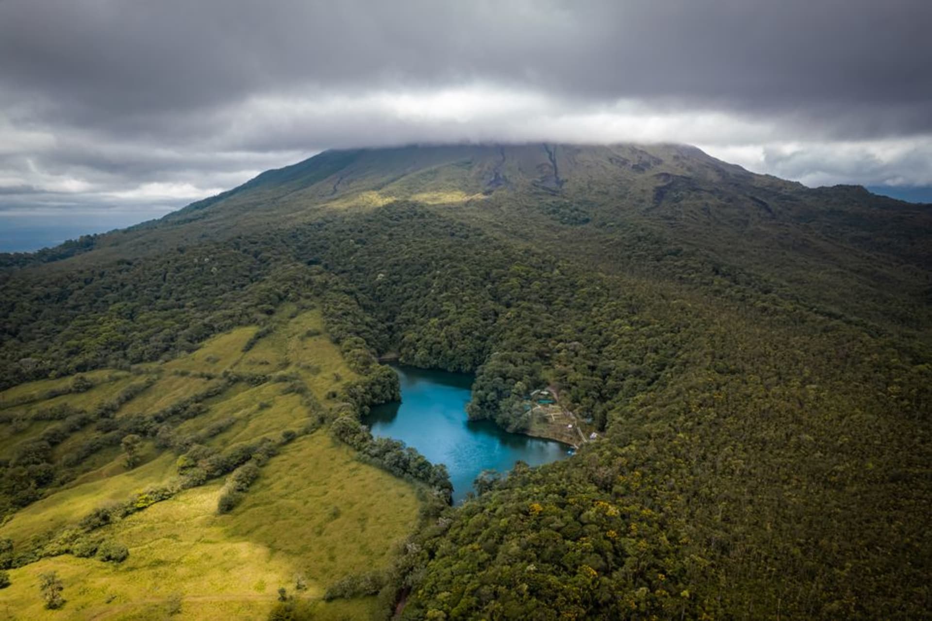 Rolling green highland pasture near the town of Volcán with the summit of Volcán Barú rising into cloud in the background.