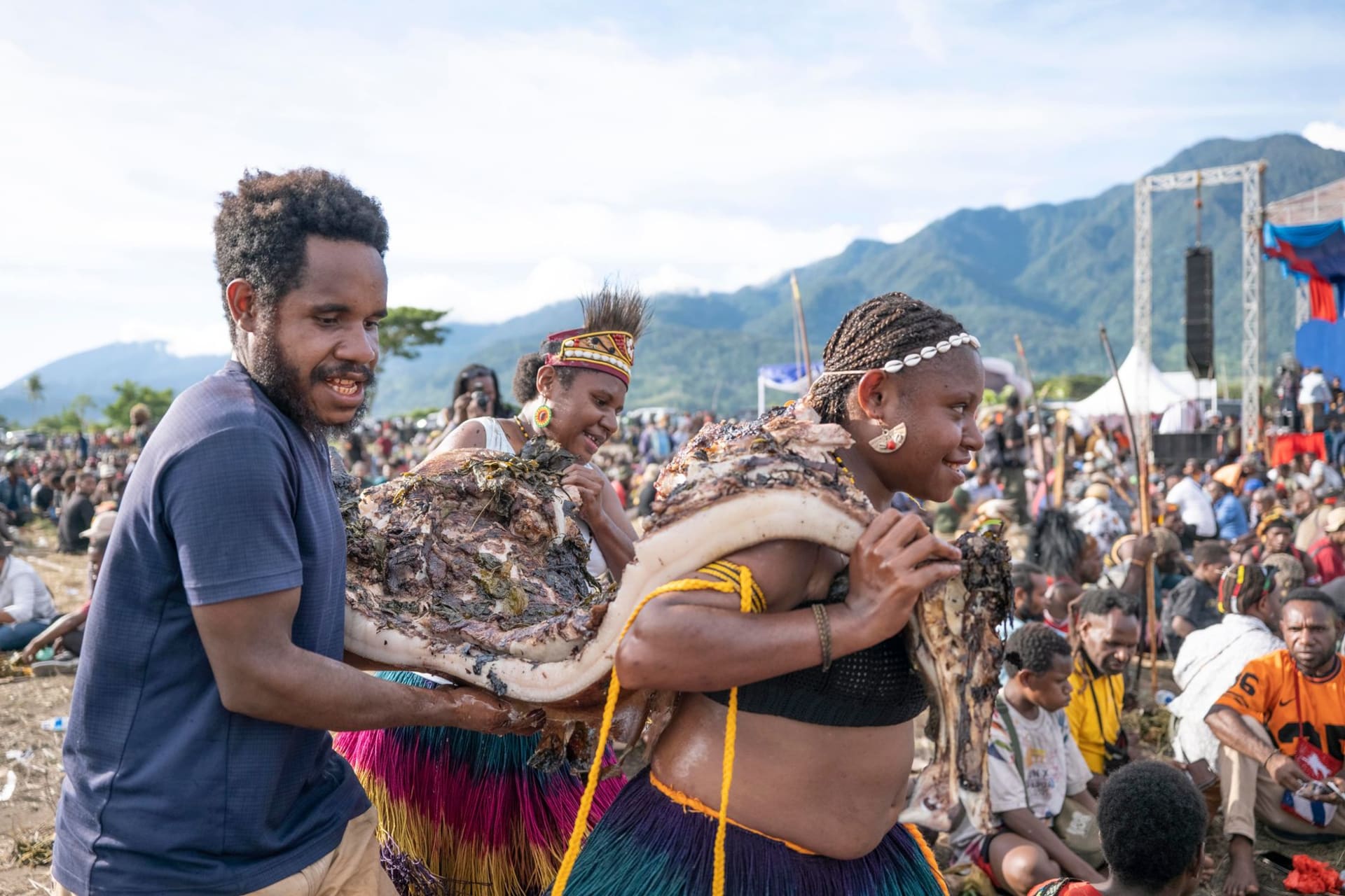 Una casa de los espíritus iatmul tradicional alzándose desde las orillas del río Sepik al atardecer, su techo en punta silueteado contra un cielo naranja reflejado en el agua marrón y tranquila