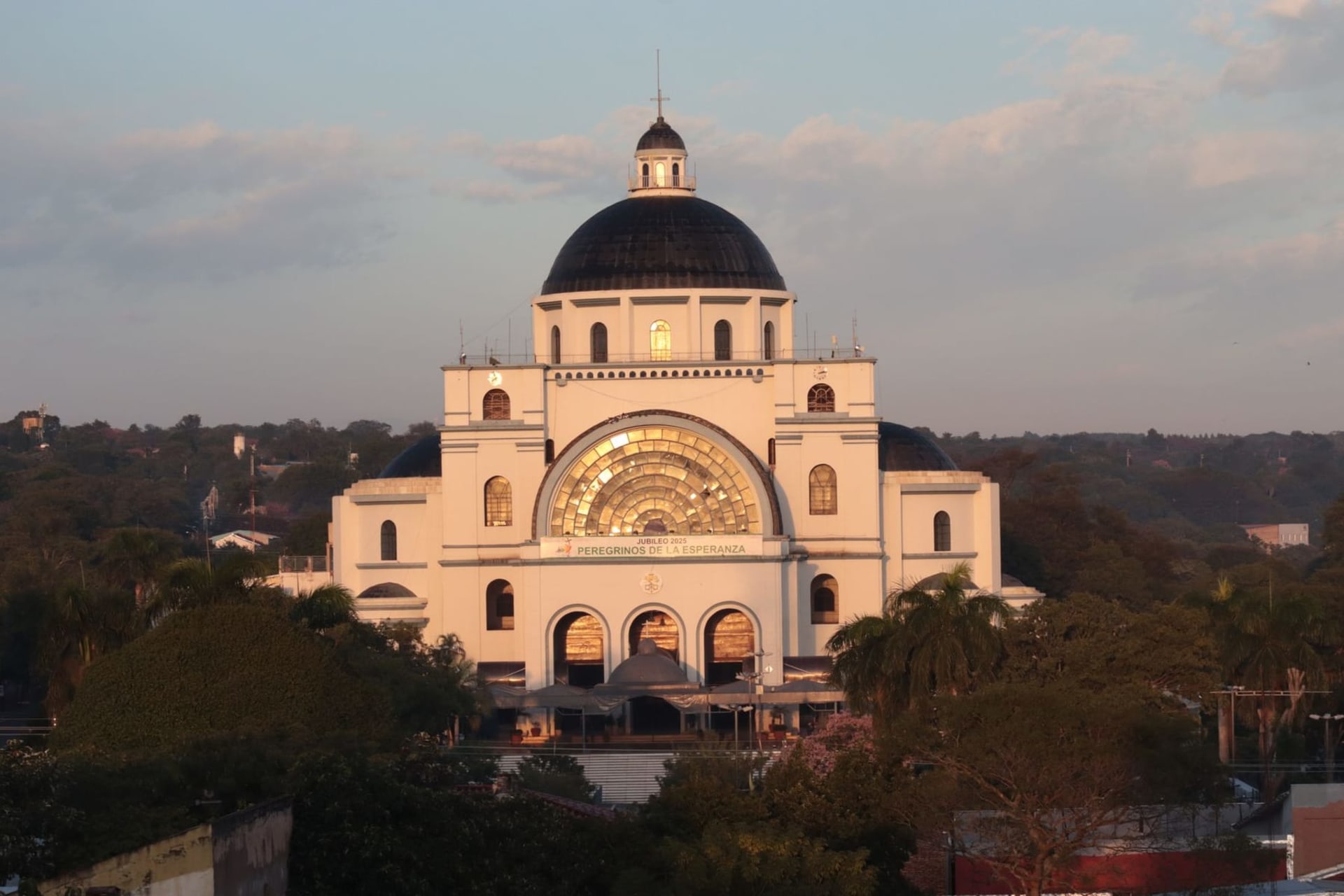 Terracotta rooftops and pale colonial facades along Asuncion's historic center, with the broad silver ribbon of the Paraguay River visible beyond the bluff edge