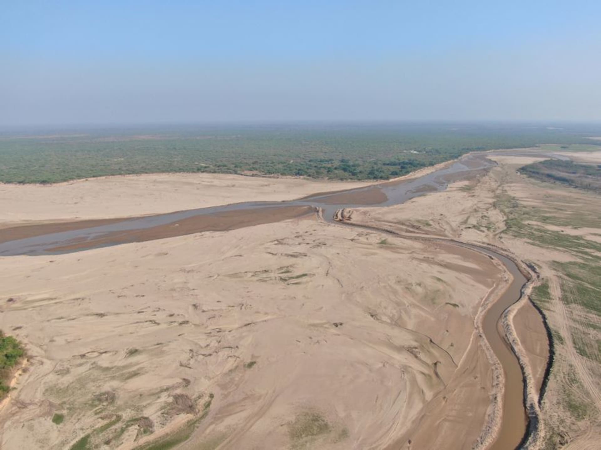 Una amplia calle de tierra en Filadelfia bordeada de edificios bajos construidos por menonitas y monte chaqueño seco extendiéndose más allá