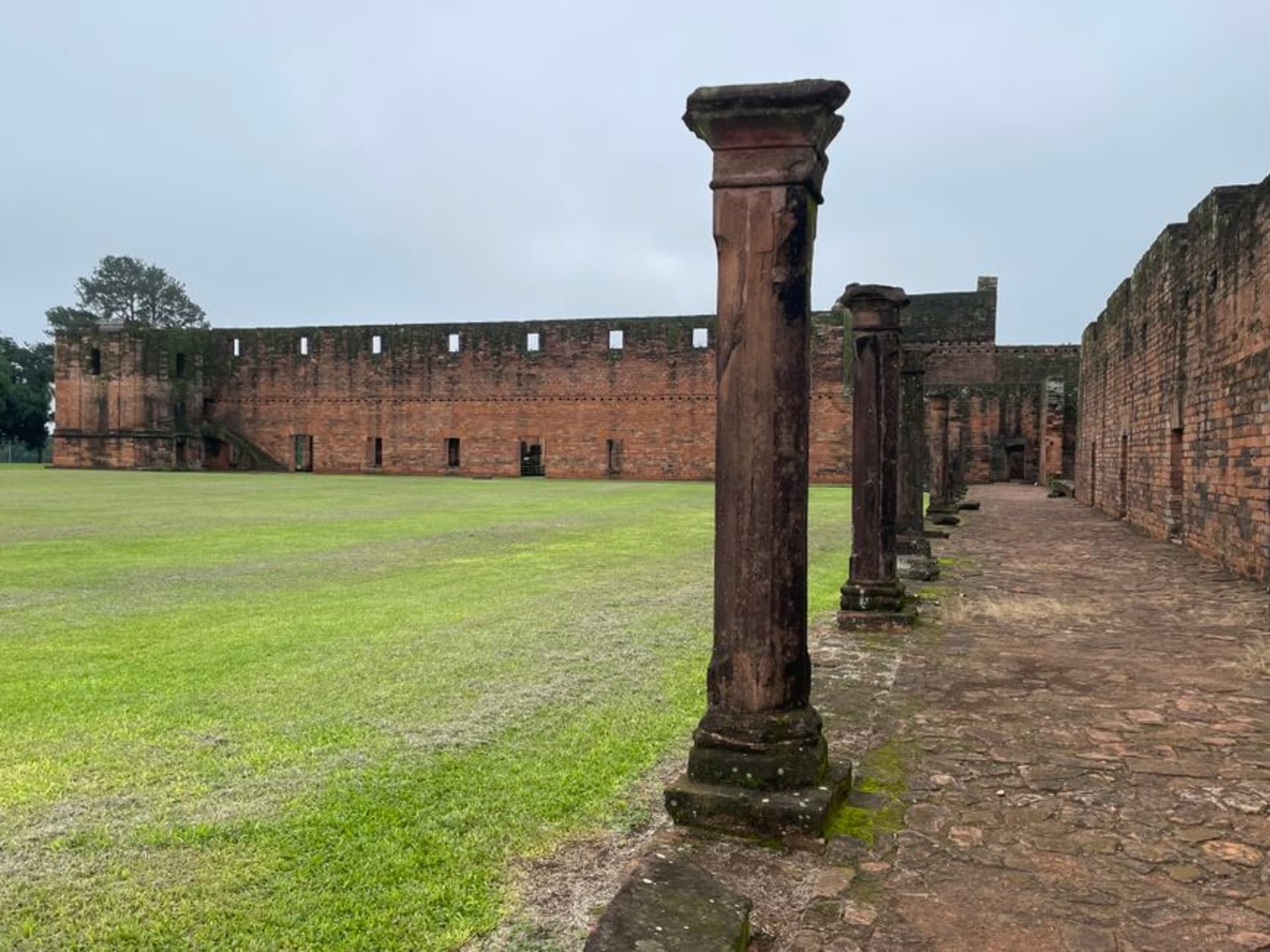 The red sandstone ruins of the Jesuit mission church at Trinidad, carved stone arches standing in open grassland under a clear sky