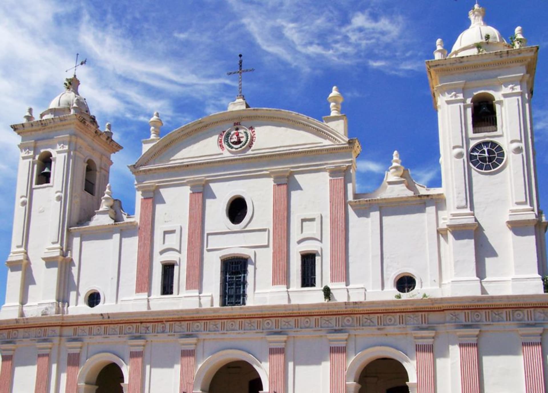 The whitewashed colonial facade of the Franciscan church in Yaguaron with its freestanding bell tower against a bright sky